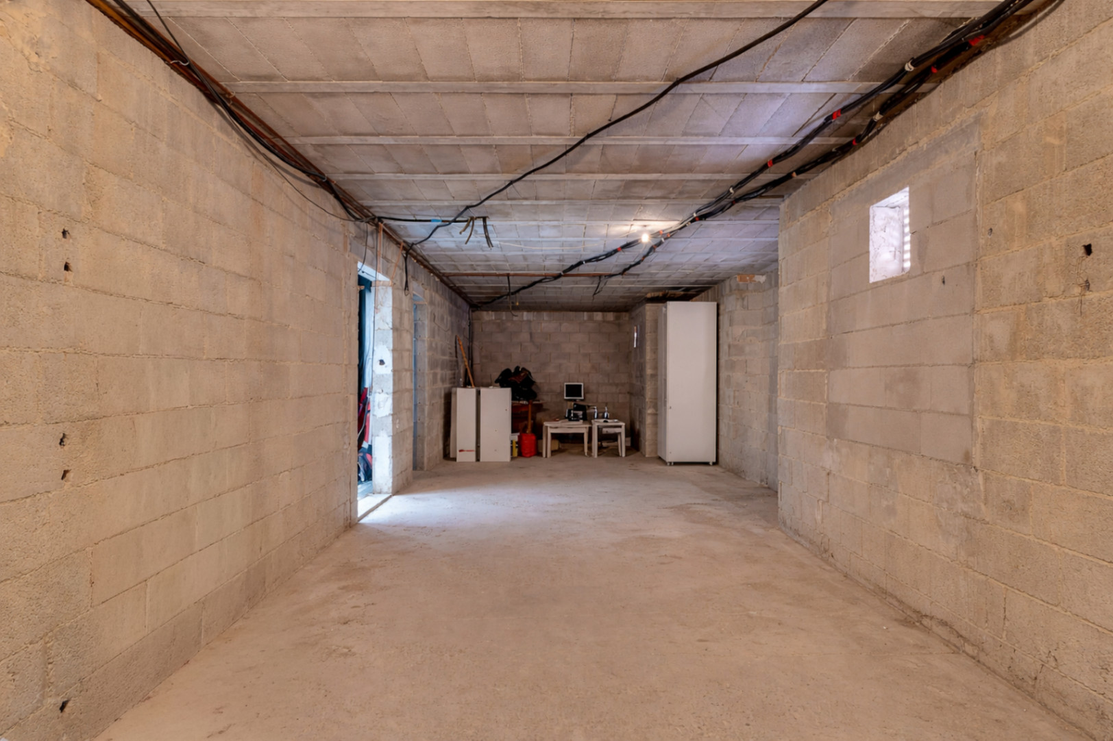 Amplio espacio diáfano en bruto con paredes de bloque de hormigón y techos altos, ideal para ampliar la vivienda con dormitorios adicionales o un gimnasio privado.