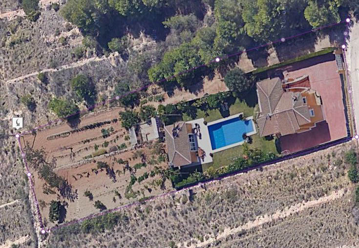 Vista aérea de la parcela delimitada que muestra la villa principal, la piscina de 15x6 m, la zona de barbacoa y la extensa zona de cultivo en un entorno natural.
