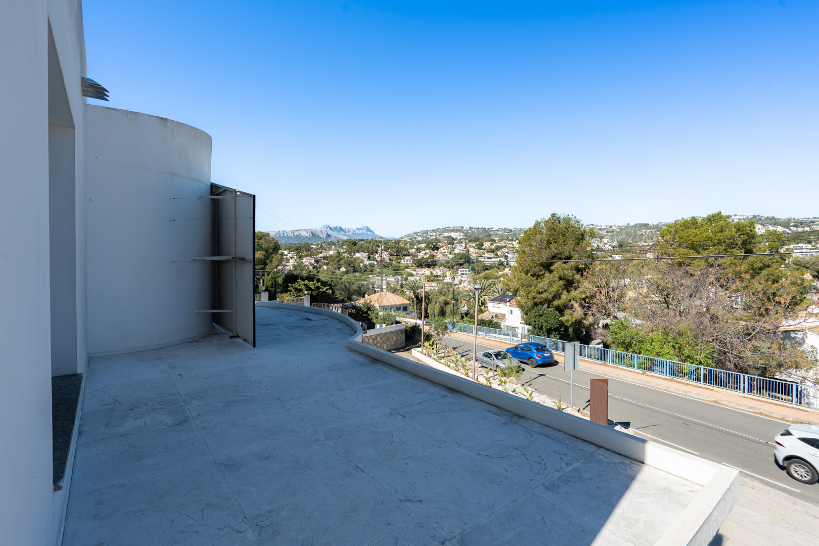 Amplia terraza con pavimento de gres claro y vistas panorámicas a la Sierra de Bernia y al entorno residencial de Moraira-Benissa.