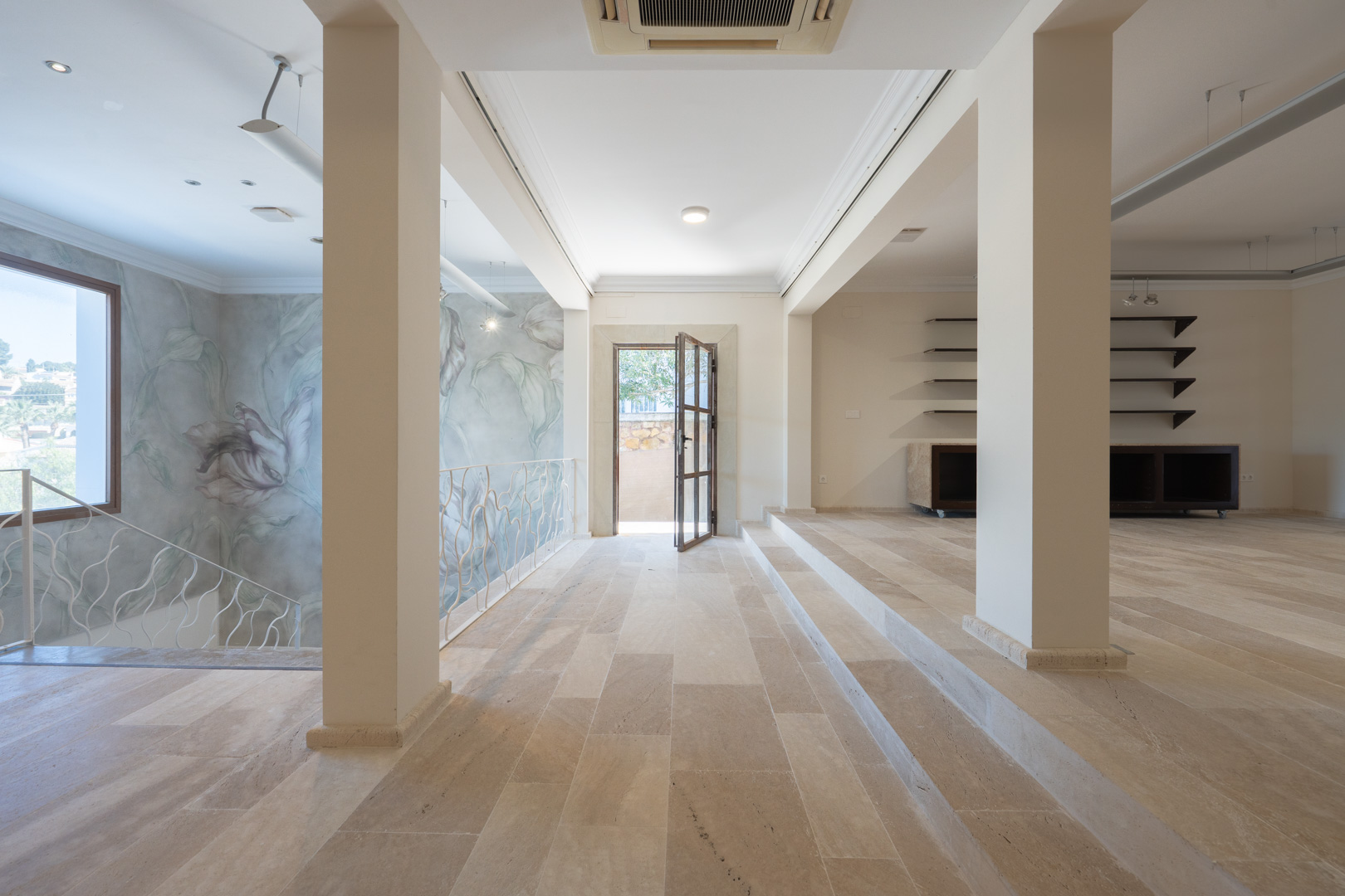 Espacioso nivel comercial con suelos de piedra, mural floral artístico y barandilla de forja blanca. Dispone de aire acondicionado central y acceso exterior.