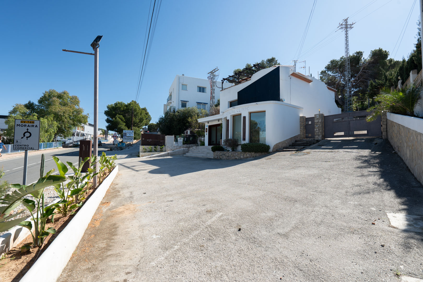 Fachada exterior del edificio comercial con amplios ventanales, zona de aparcamiento privada y acceso directo desde la carretera CV-746 en Moraira.