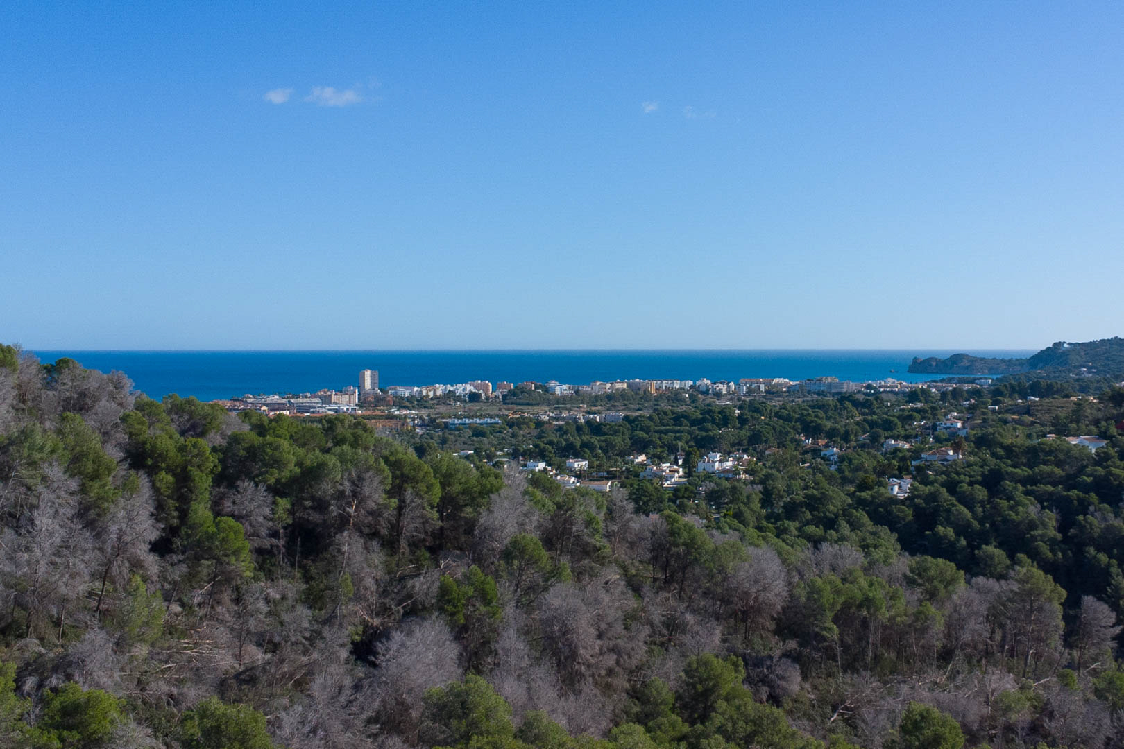 Vistas panorámicas desde la propiedad hacia el mar Mediterráneo y el núcleo urbano, rodeado de un entorno forestal de pinos bajo un cielo despejado.