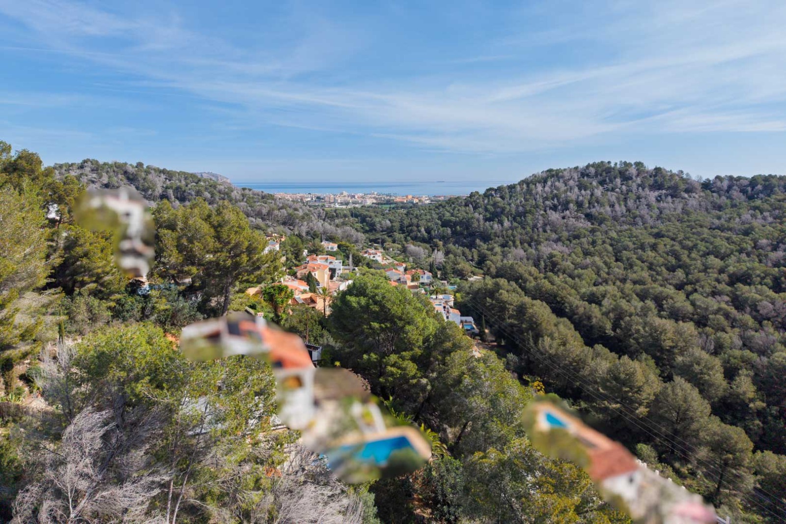 Vistas panorámicas desde la parcela hacia las colinas boscosas de pinos y el mar Mediterráneo, con el núcleo urbano de Jávea en el horizonte.