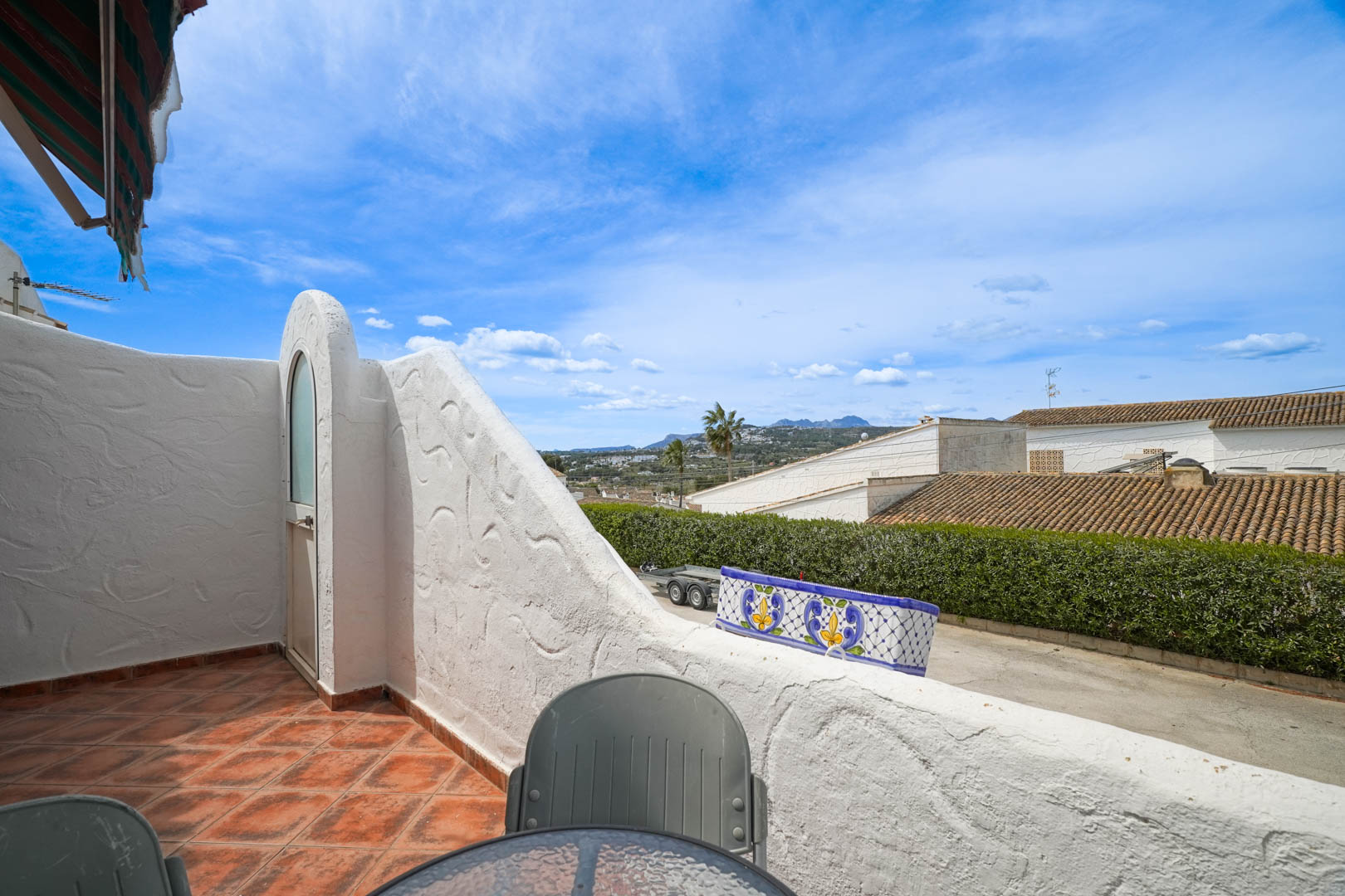 Terraza elevada con suelo de gres rústico y vistas despejadas al valle de Moraira. Incluye un práctico trastero exterior integrado en el muro de mampostería blanca.