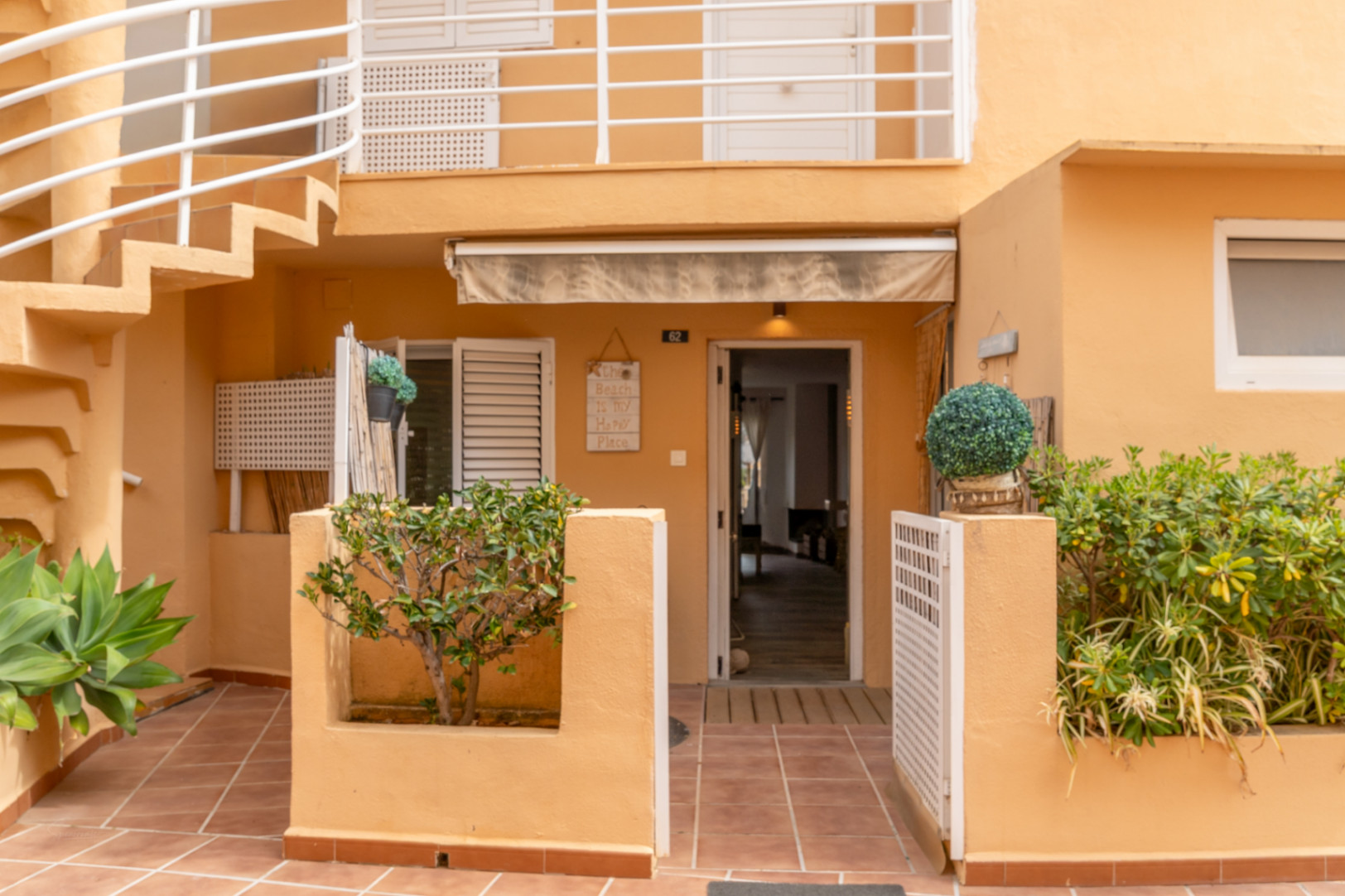 Entrada a un apartamento en planta baja con terraza y escalera exterior.