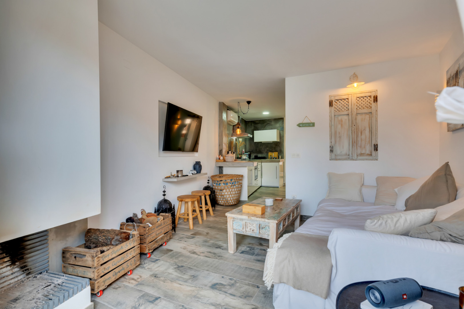 Salón con chimenea, cocina abierta y suelo de gres imitación madera.