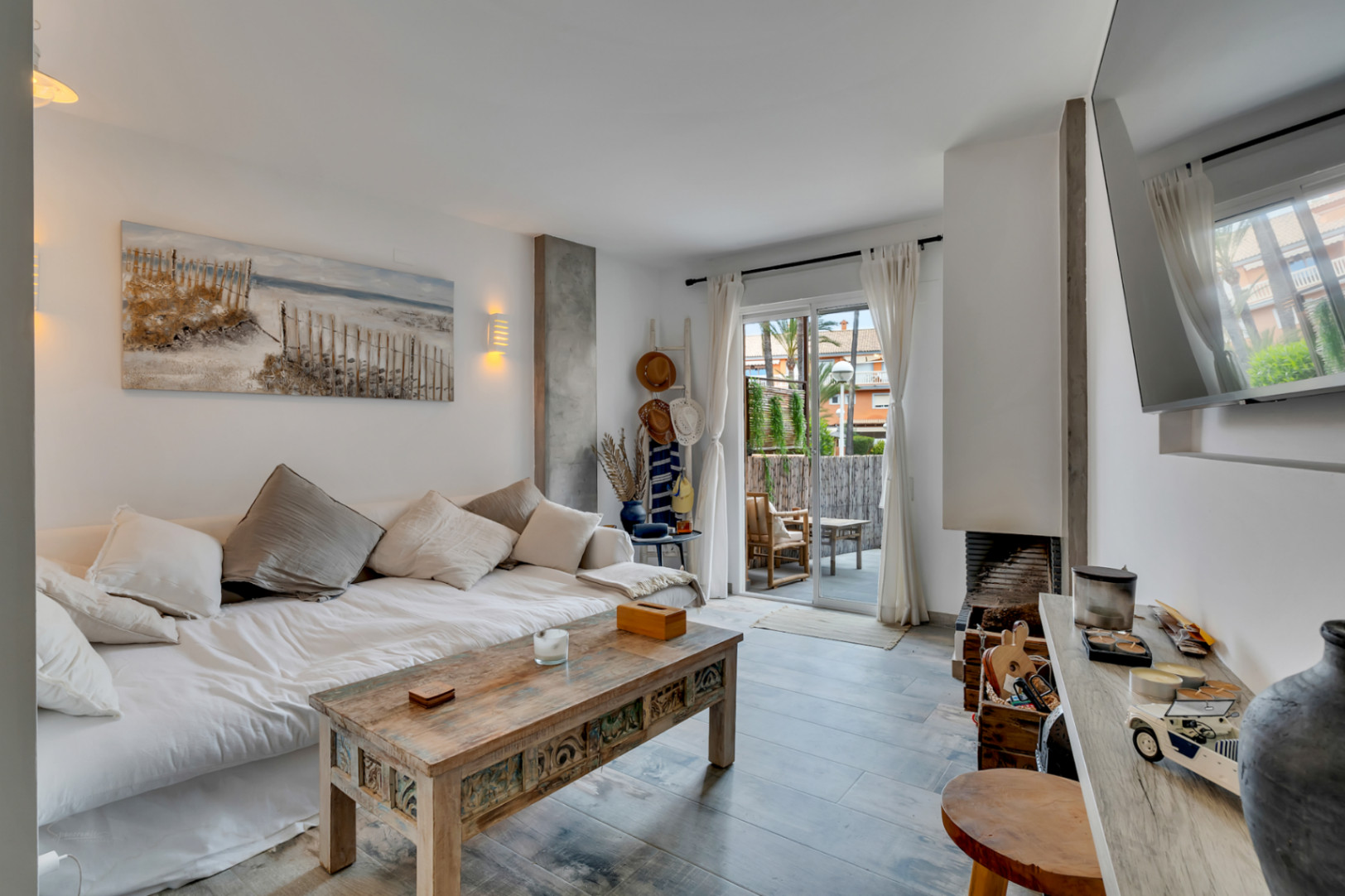 Salón luminoso con sofá cama, mesa de centro de madera tallada y acceso a la terraza.