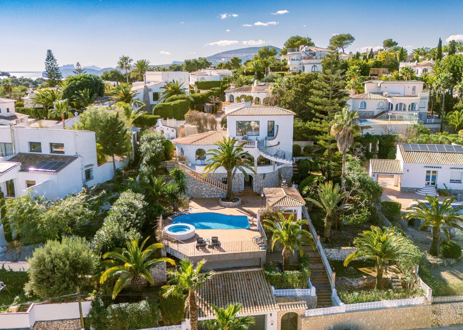 Vista aérea de la villa en Balcón al Mar mostrando sus tres niveles, piscina con jacuzzi integrado, terrazas de piedra y jardín mediterráneo con palmeras y vistas despejadas.