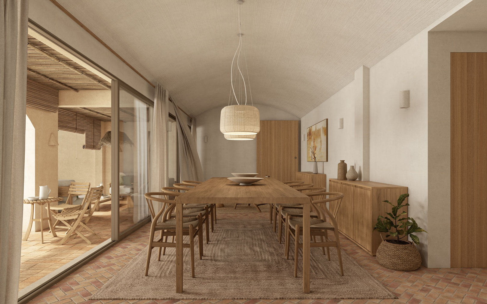 Comedor con techo abovedado, mesa de madera y sillas Wishbone sobre suelo de terracota. Grandes ventanales conectan el espacio con una terraza cubierta de estilo mediterráneo.