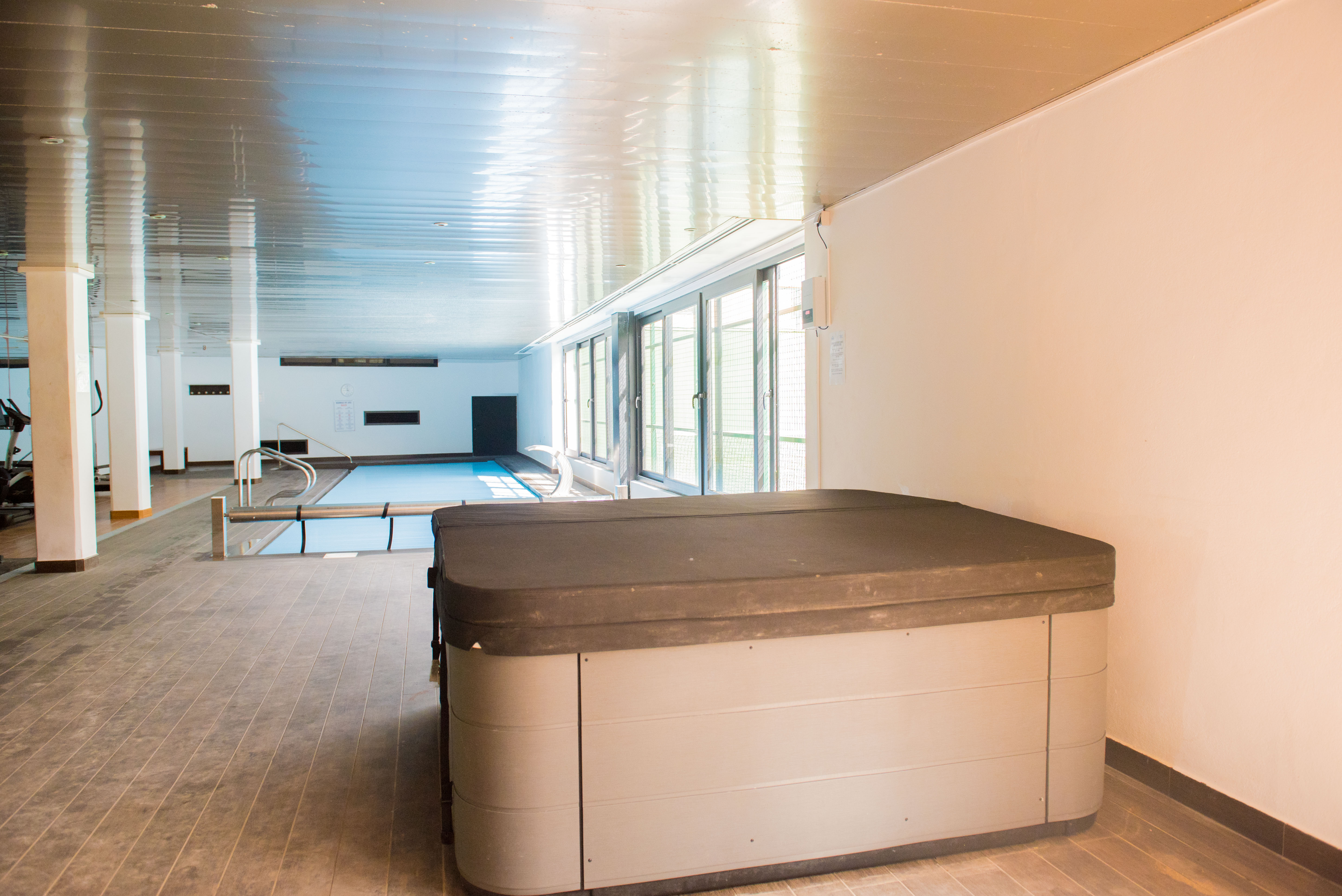 Jacuzzi cubierto en primer plano, con piscina interior climatizada y ventanales que aportan luz natural a esta zona wellness. Jacuzzi cubierto en primer plano, con piscina interior climatizada y ventanales que aportan luz natural a esta zona wellness.