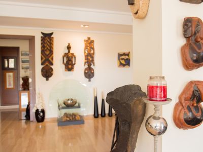 Un interior artístico que exhibe una colección curada de máscaras y bustos de madera tallada en paredes claras, complementado por un suelo de madera pulida y detalles decorativos modernos.