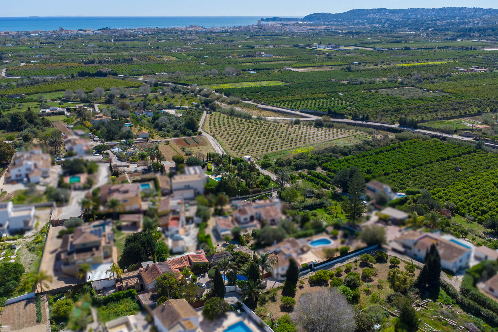 Vista aérea que muestra la ubicación de la propiedad rodeada de campos agrícolas, con el mar Mediterráneo y la costa de Jávea en el horizonte.