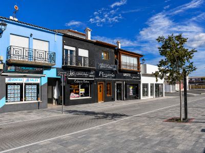 Fachadas coloridas de locales comerciales en Els Poblets, con balcones de hierro forjado y toldos.