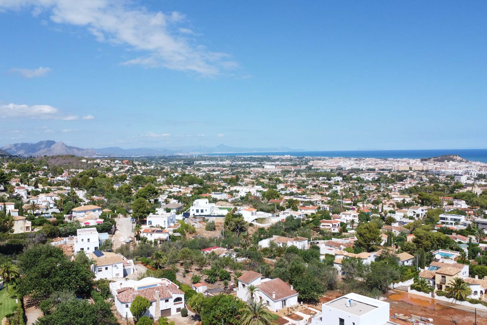Vista aérea panorámica de la zona residencial en Dénia, destacando la proximidad al mar Mediterráneo y la integración de las viviendas en el paisaje costero.