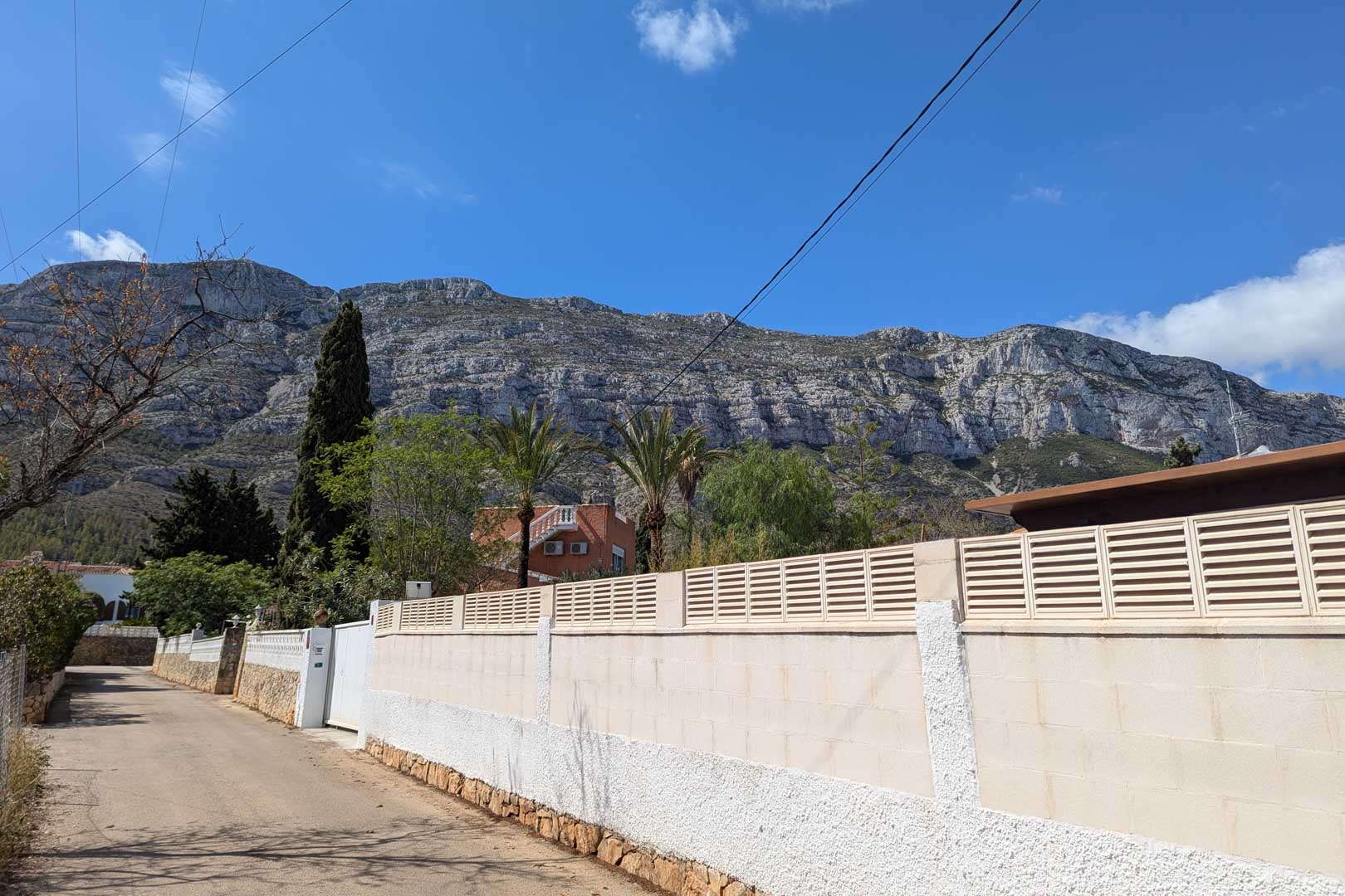 Vista exterior desde la calle que muestra el muro perimetral de la parcela con el imponente macizo del Montgó como telón de fondo natural.
