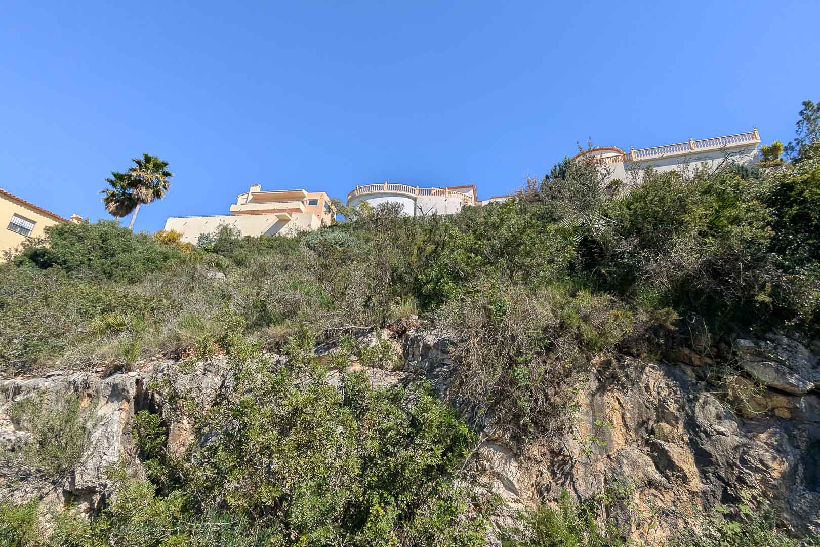 Vista de la villa en construcción desde la base rocosa, mostrando su integración en el paisaje.