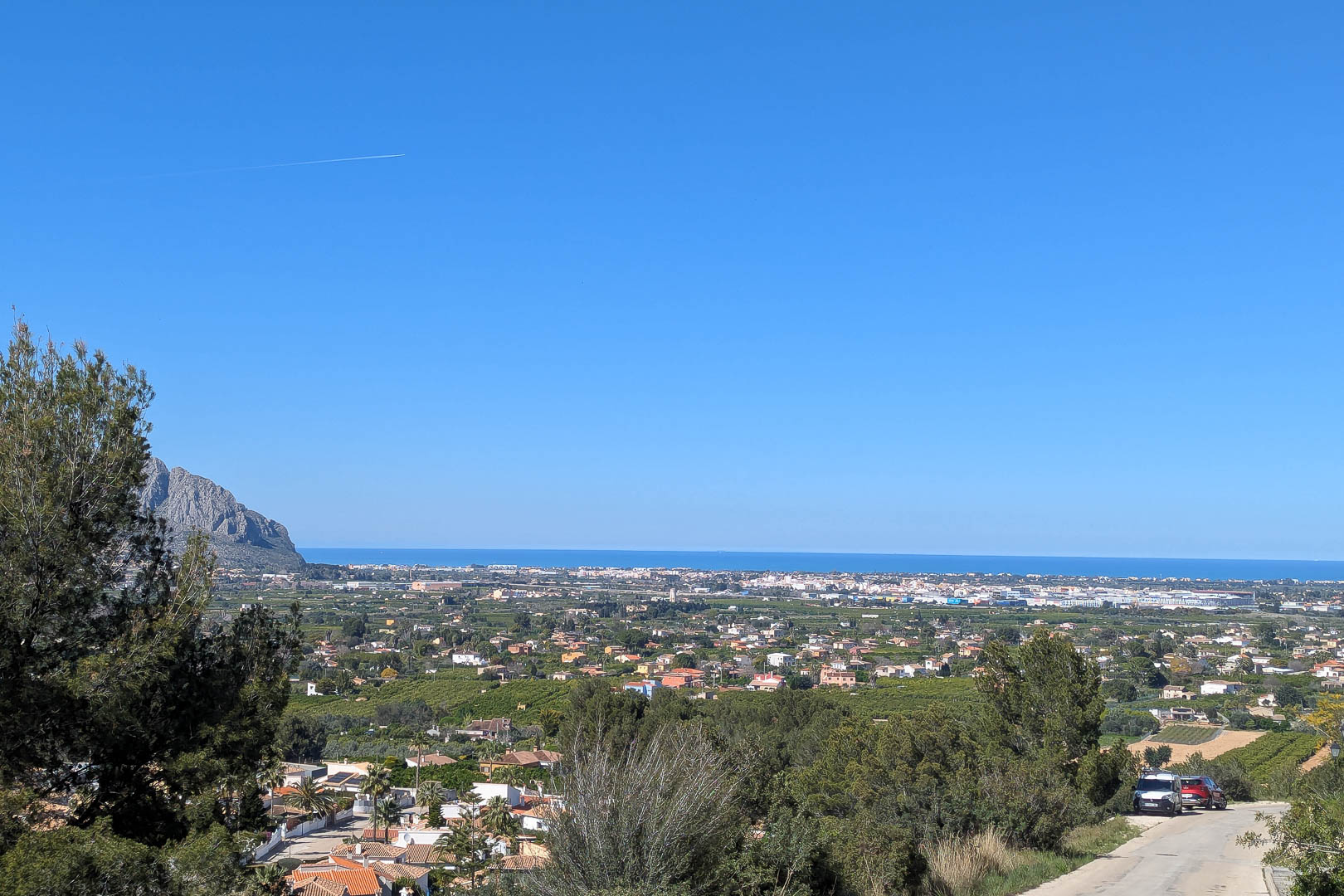 Vista panorámica de Pedreguer, con el mar Mediterráneo al fondo y vegetación exuberante en primer plano.