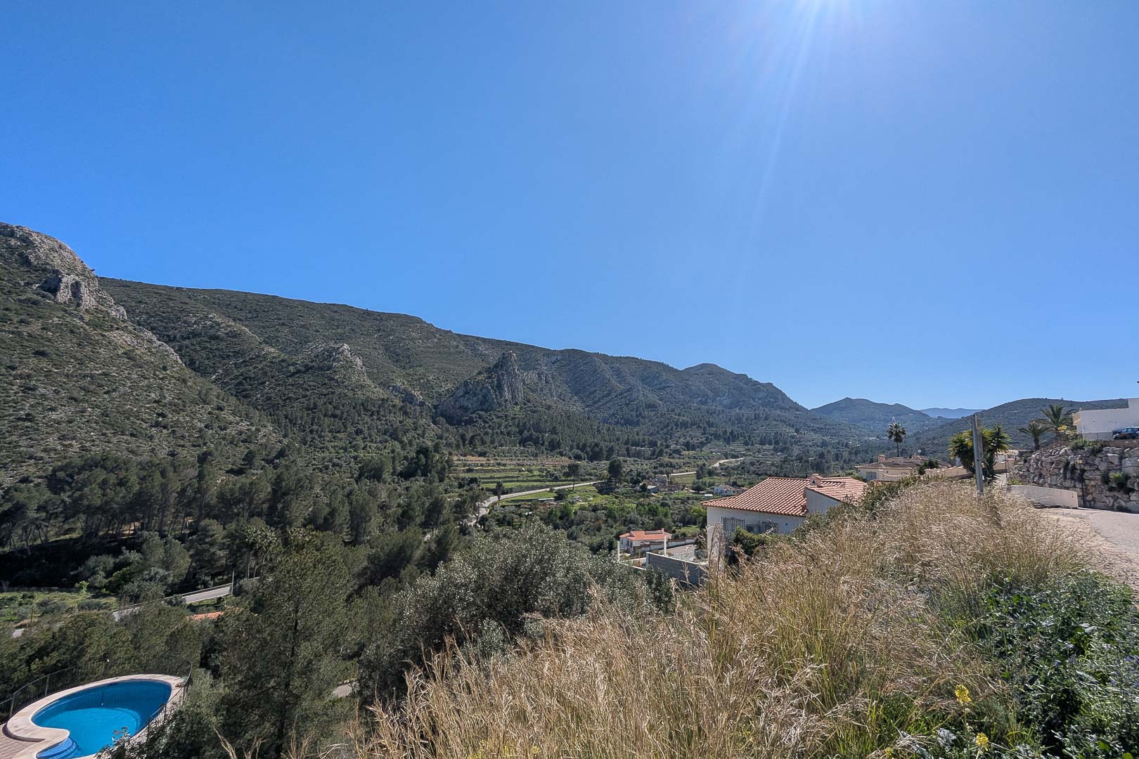 Vistas panorámicas a las montañas y al valle de Pedreguer desde una posición elevada, destacando el entorno natural y la vegetación mediterránea bajo un cielo despejado.