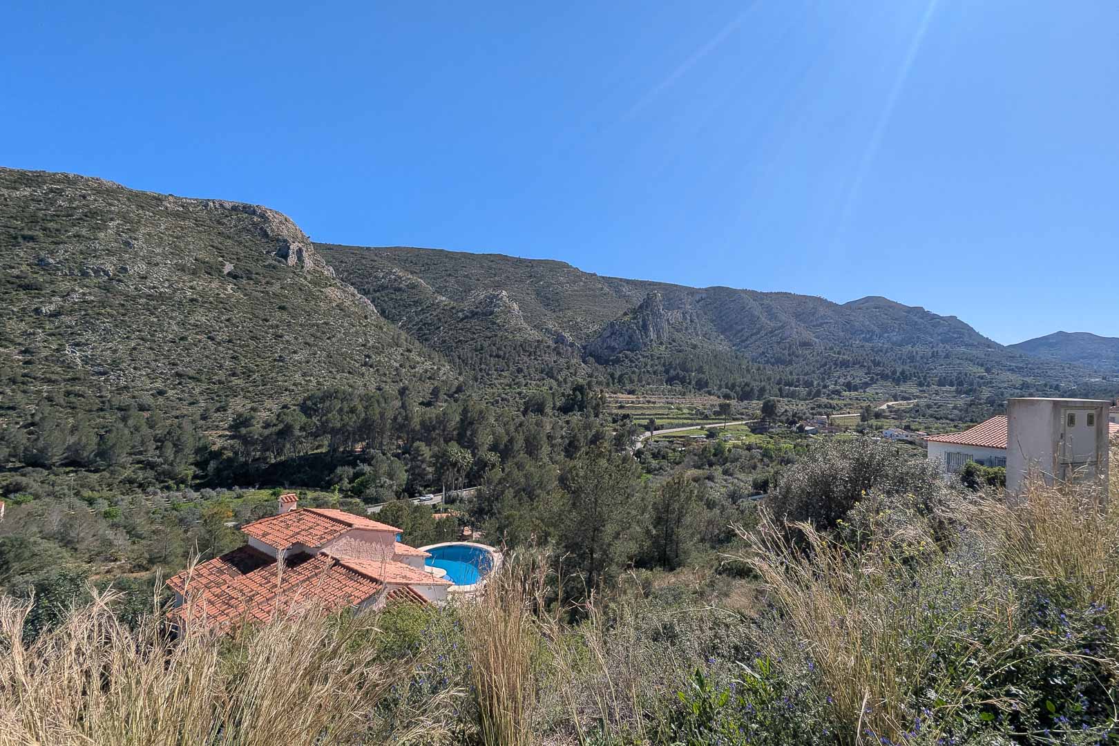 Vistas panorámicas desde la propiedad hacia el valle y las montañas de Pedreguer, con vegetación mediterránea y una piscina privada en el entorno natural.