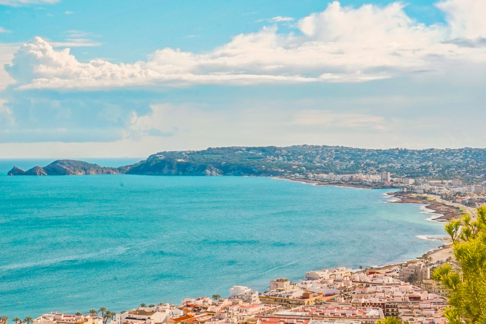 Vista panorámica de la bahía de Jávea desde la urbanización La Corona, destacando el litoral urbano y el perfil del Cap Negre sobre el mar Mediterráneo.