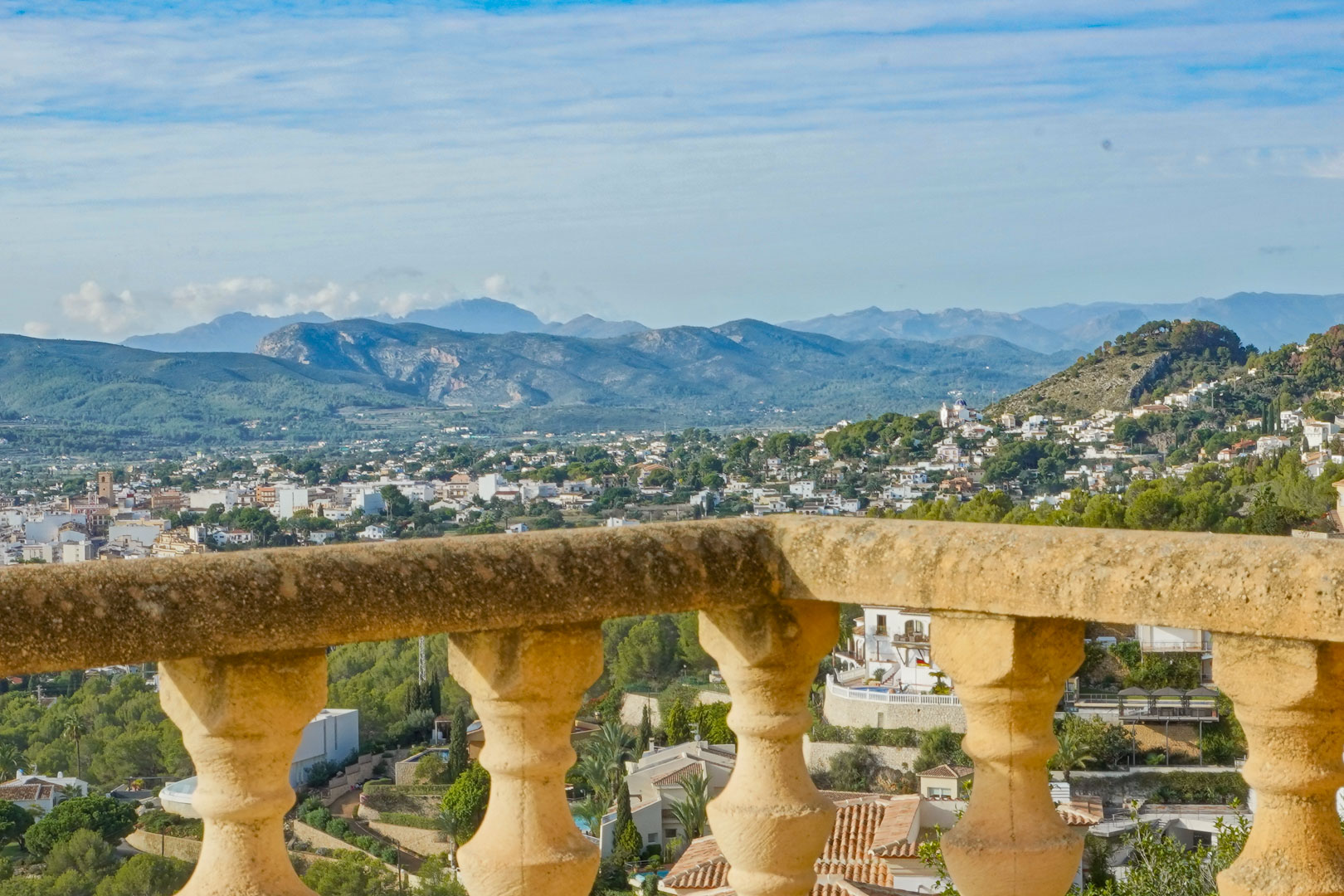 Vista panorámica desde la terraza con balaustrada de piedra tradicional, orientada hacia el valle de Jávea y las montañas circundantes bajo un cielo despejado.