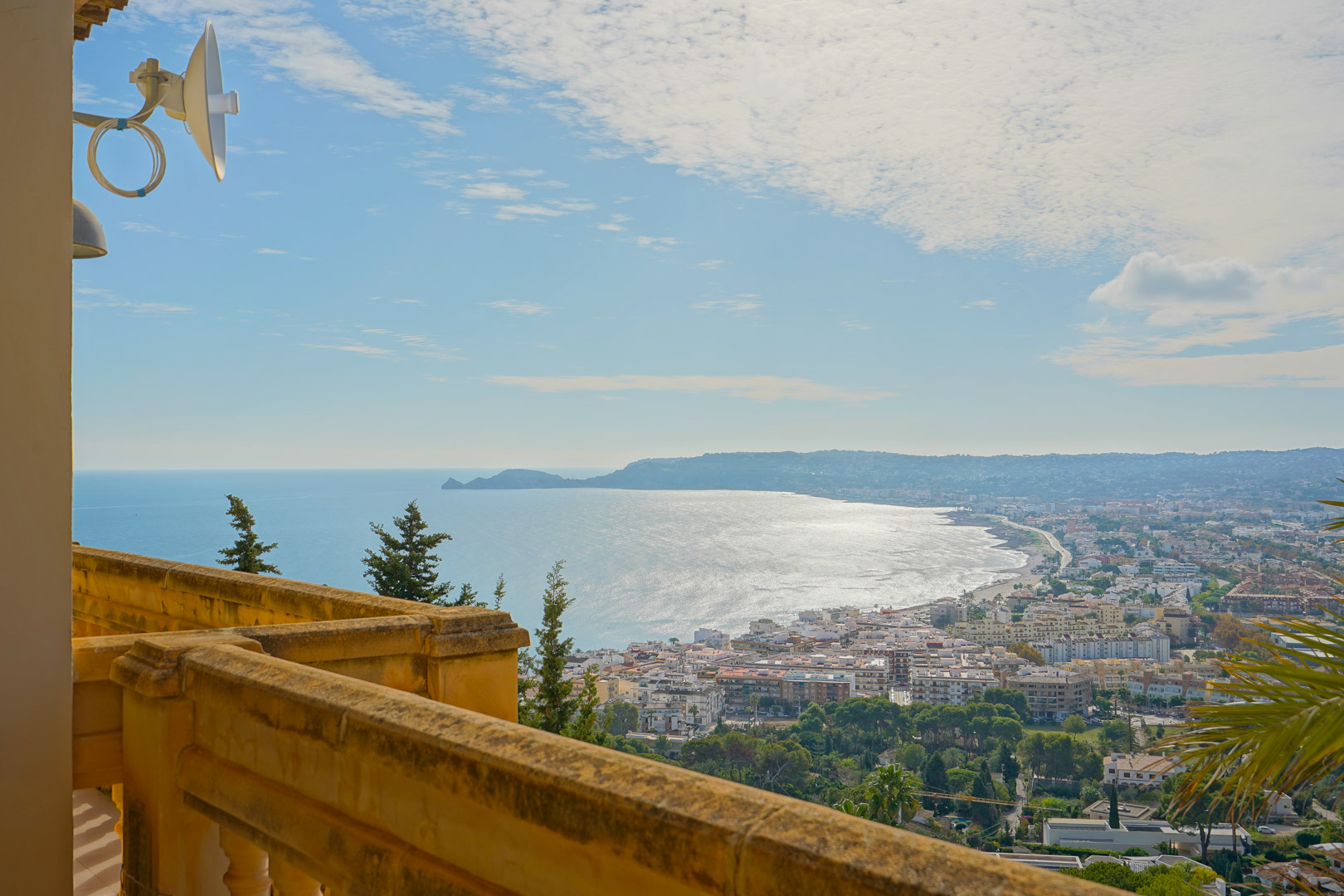 Vista panorámica desde la terraza superior sobre la bahía de Jávea y el Cap Negre, destacando la balaustrada de piedra tradicional y el entorno costero.