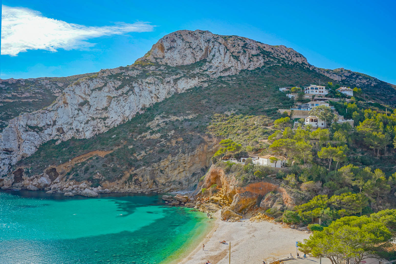 Vista panorámica de la Cala Granadella con sus aguas turquesas, acantilados calizos y vegetación mediterránea autóctona rodeando la playa de guijarros.
