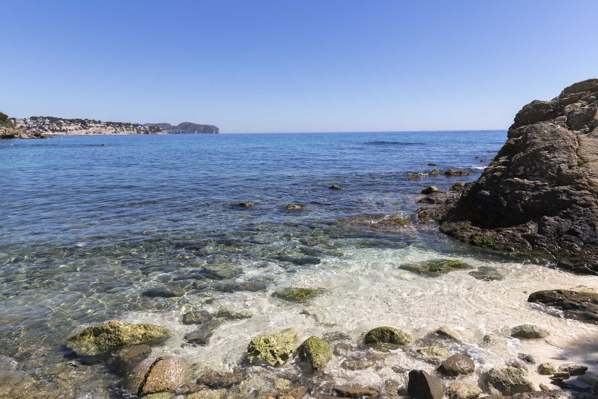 Vista de la costa mediterránea con aguas cristalinas y fondo rocoso cerca de la playa de La Fustera, destacando la proximidad del proyecto al mar.