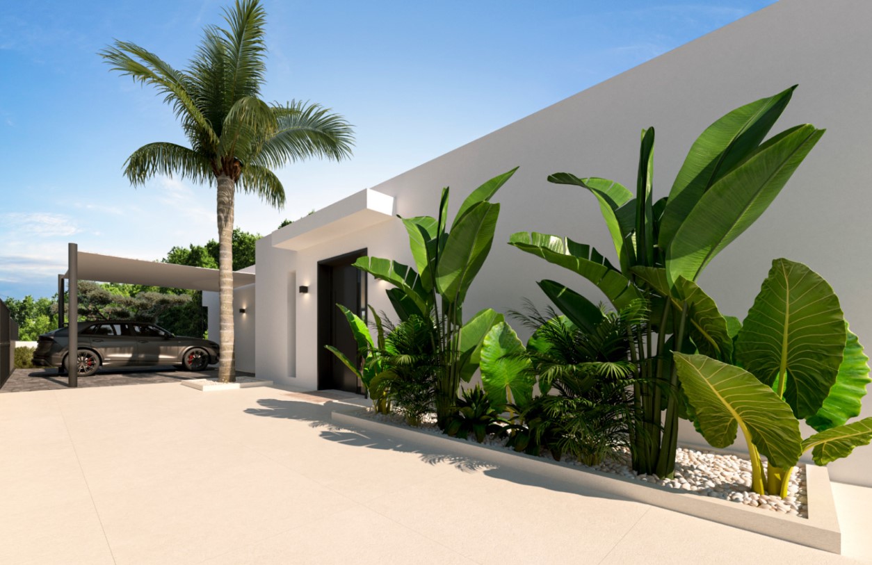 Entrada principal de diseño minimalista con puerta oscura, jardineras de piedra blanca con plantas tropicales y zona de aparcamiento cubierta junto a una palmera.