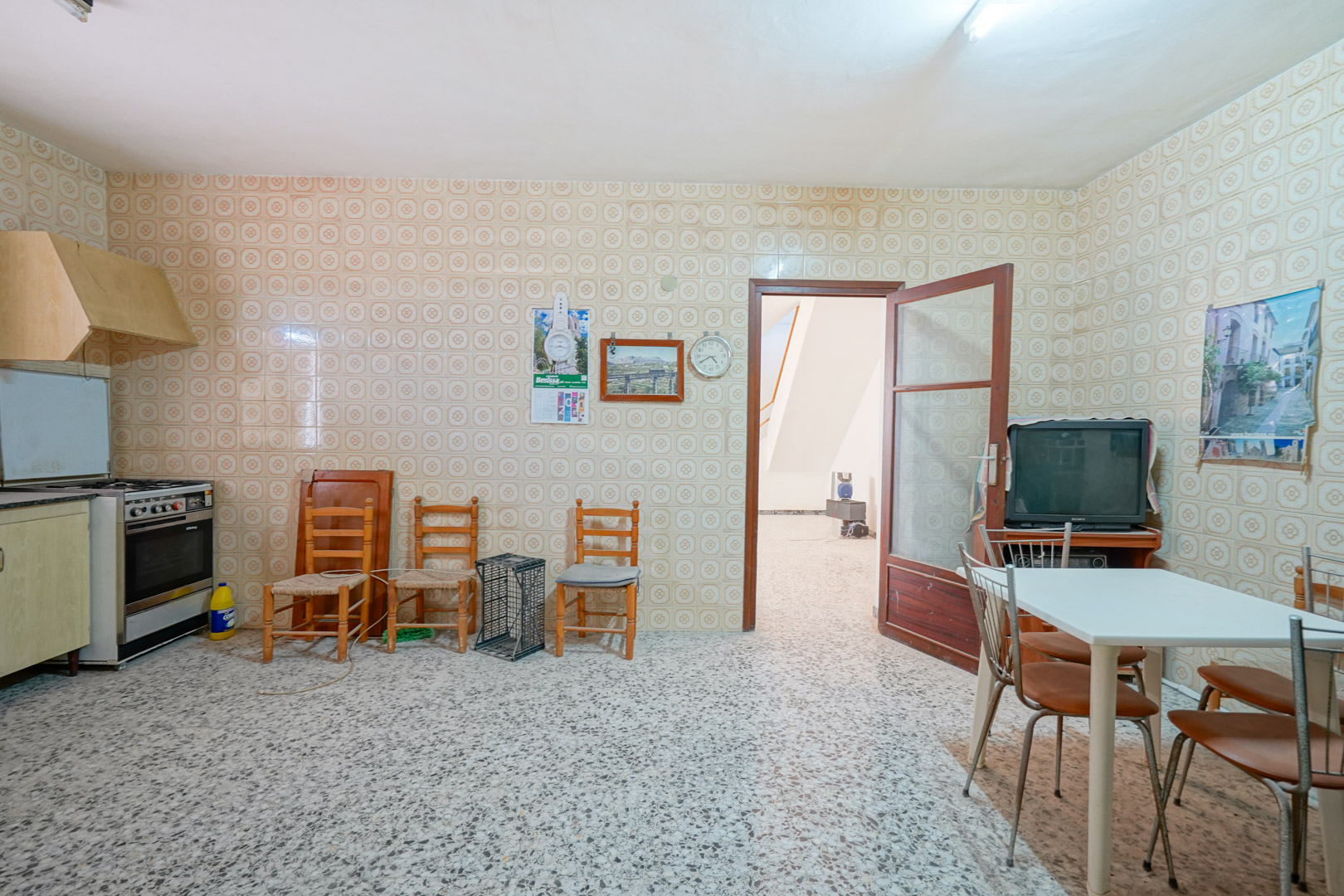Cocina tradicional con paredes alicatadas de época, suelos de terrazo y una zona de comedor integrada que conecta con el pasillo principal.
