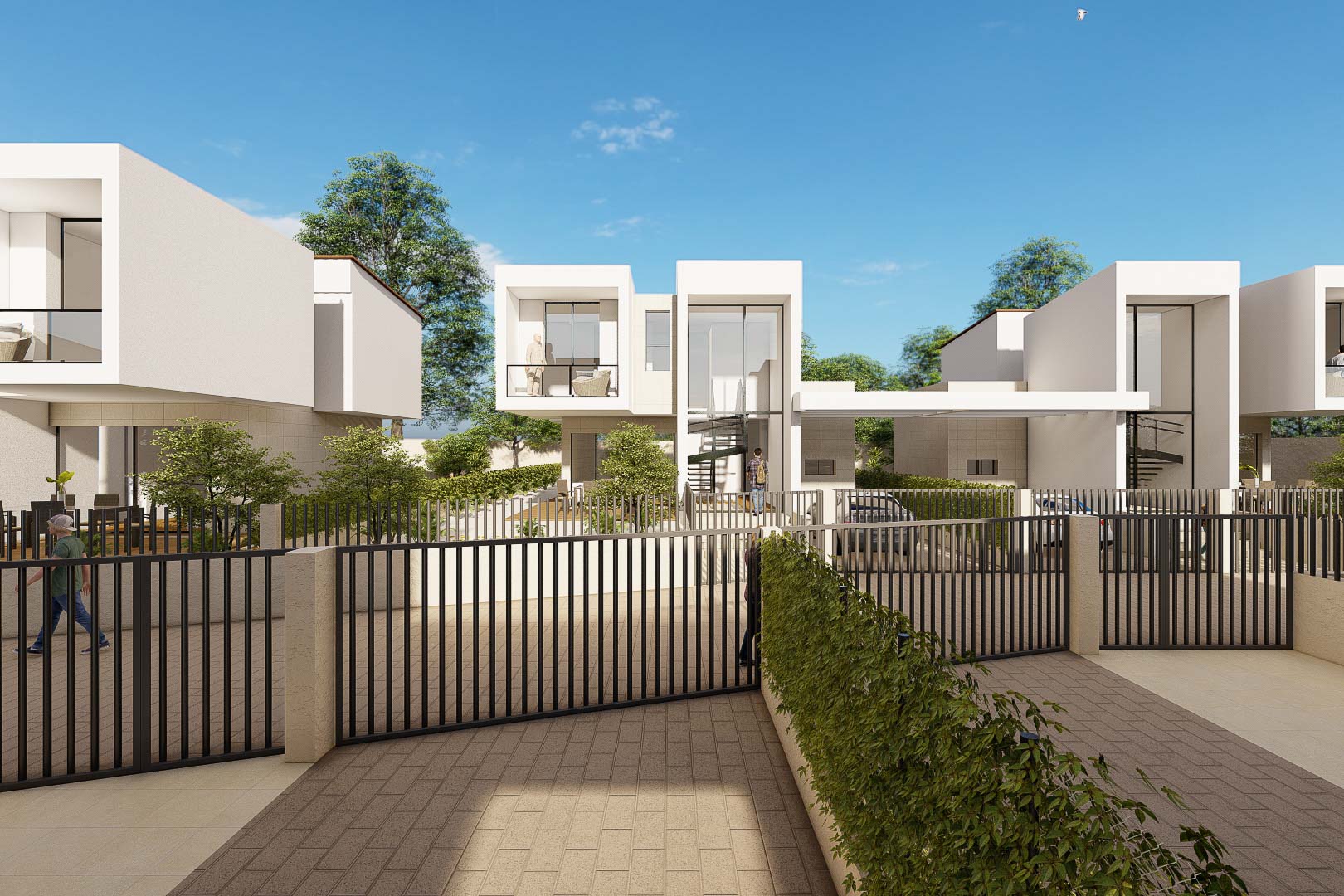 Vista exterior de las villas con fachadas blancas, grandes ventanales y vallado metálico negro. Destaca la arquitectura cúbica y el acceso pavimentado privado al complejo.