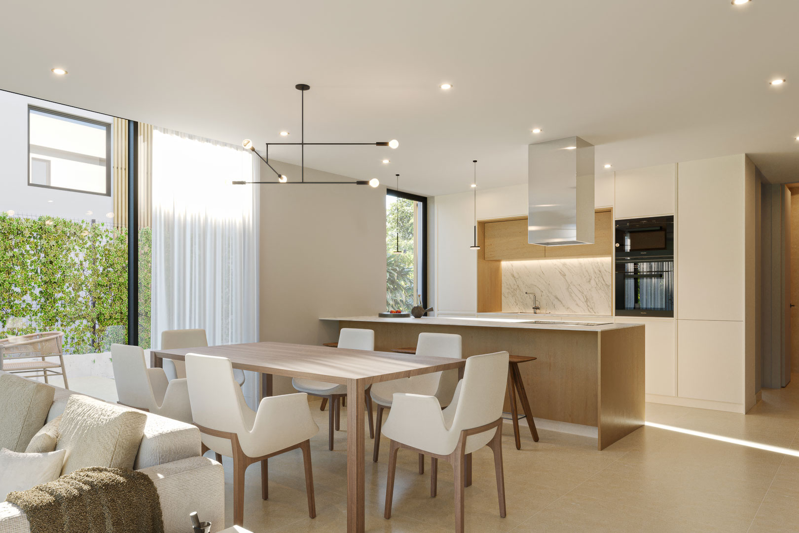 Salón-comedor diáfano con cocina integrada, isla de madera, encimera de mármol y grandes ventanales que aportan luz natural y vistas al jardín.