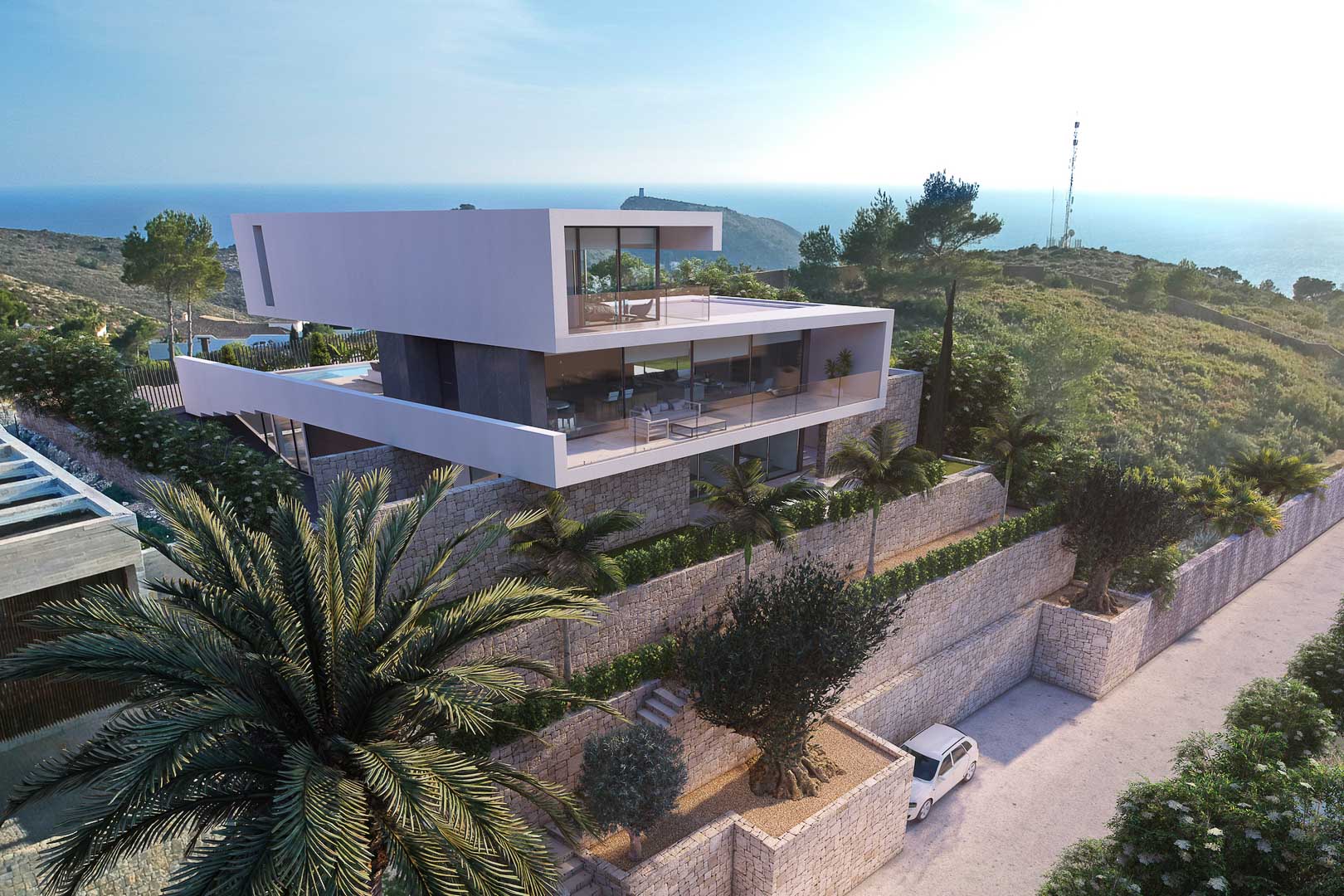 Vista exterior de la villa moderna con muros de piedra, terrazas acristaladas y vistas al mar.