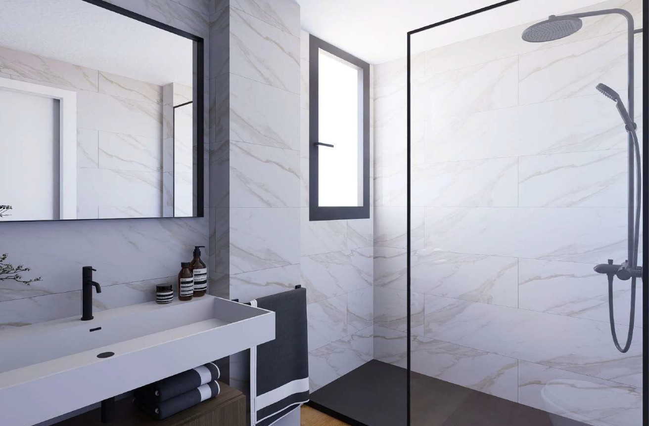 Baño moderno con azulejos de efecto mármol de Porcelanosa, ducha de obra con perfilería negra y lavabo integrado con grifería de diseño en tono oscuro.