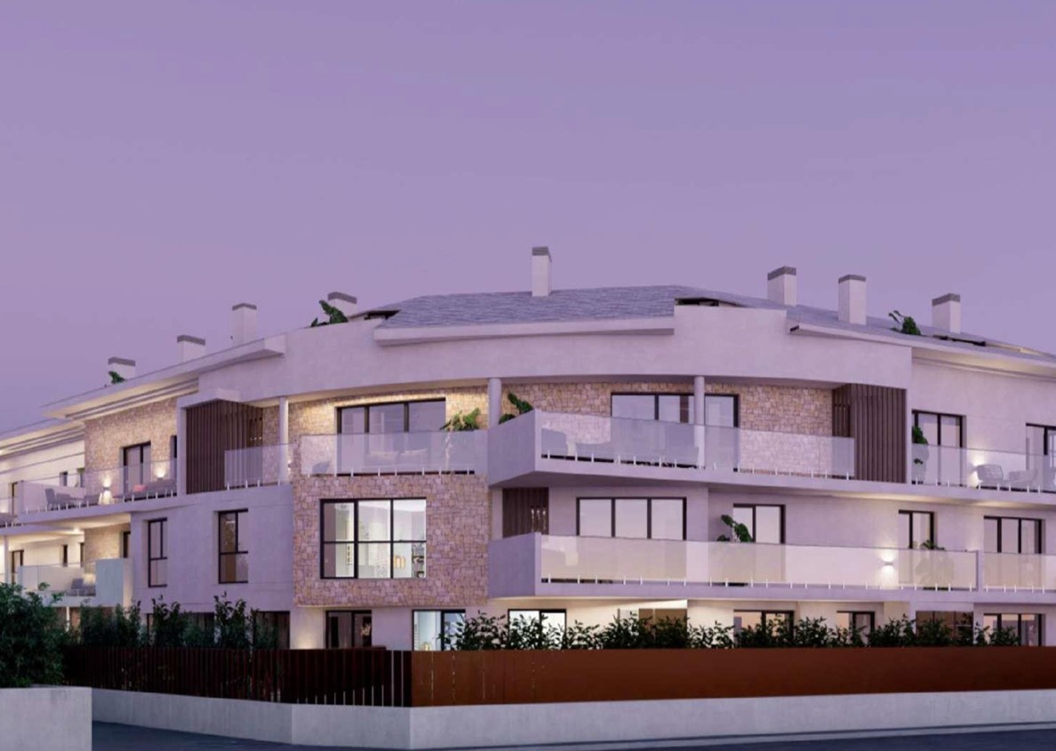 Fachada exterior del complejo residencial en Jávea, destacando el revestimiento de piedra natural, amplias terrazas con barandillas de cristal e iluminación integrada al atardecer.