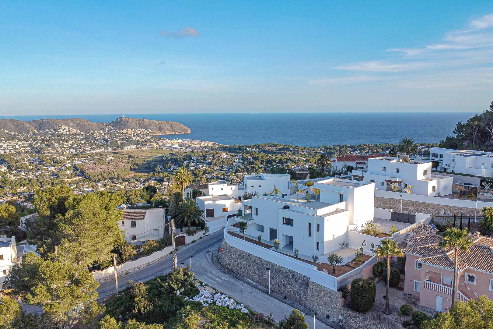 Vista aérea de villa moderna blanca en Benimeit con vistas panorámicas al mar y paisaje urbano.