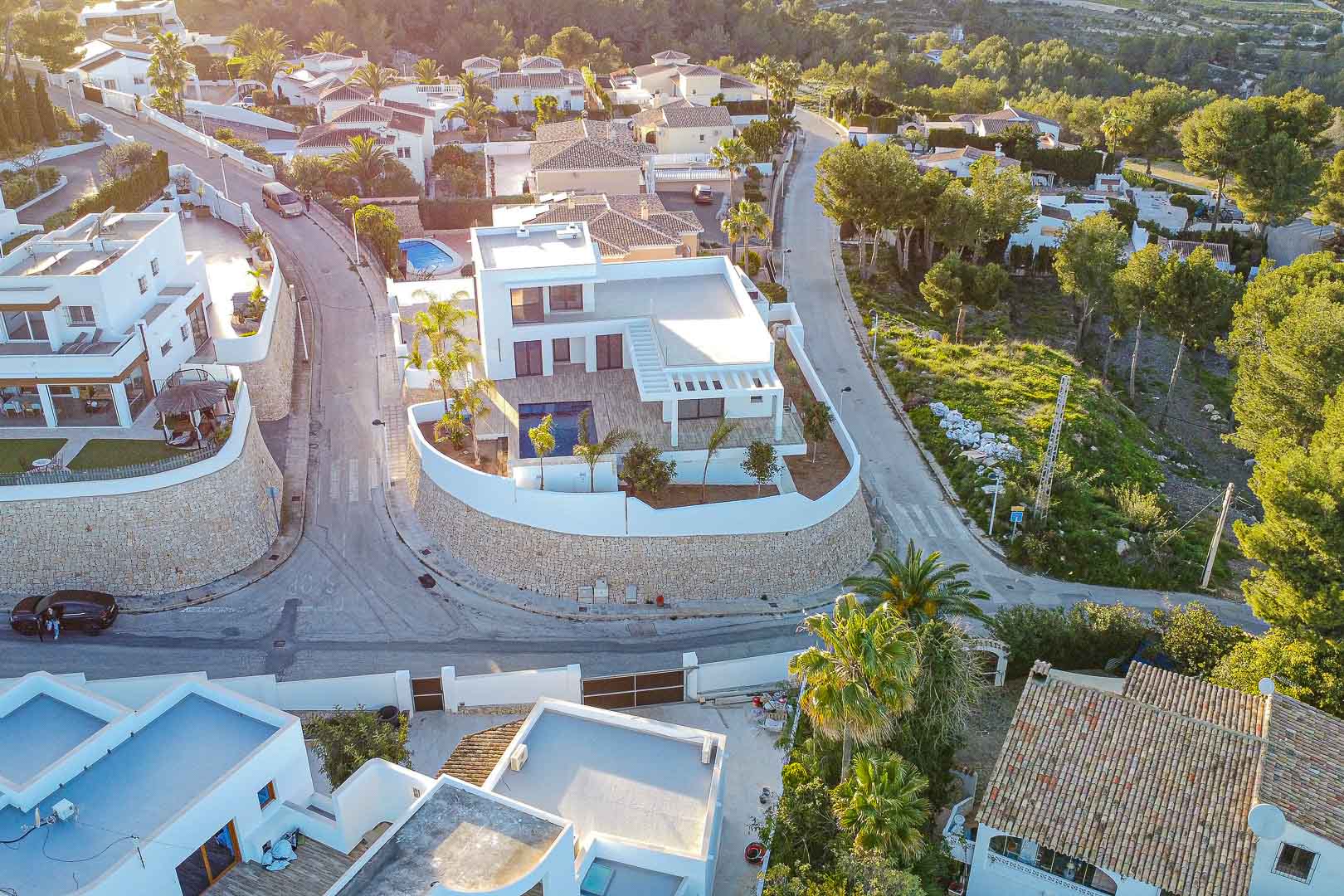 Vista aérea de villa moderna con piscina, rodeada de muro de piedra y jardines en Benimeit, Moraira.