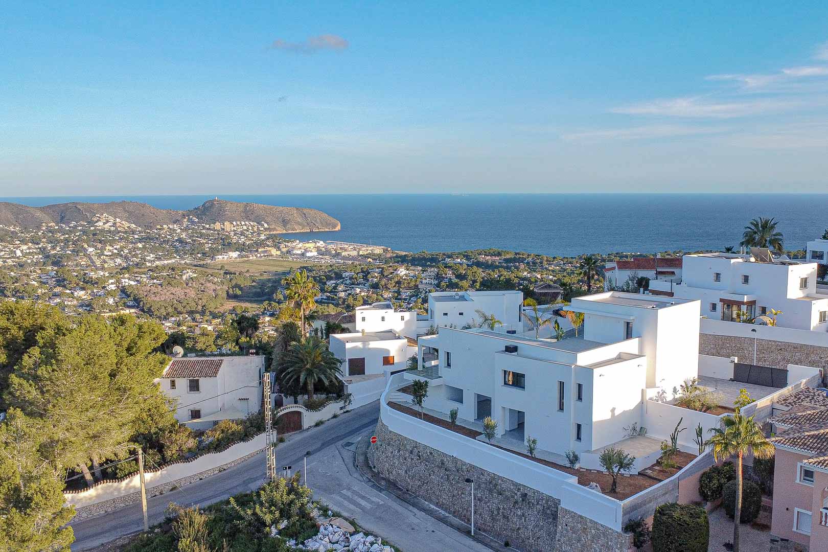 Vista elevada de villas blancas modernas en Benimeit con vistas panorámicas al mar y a la costa.