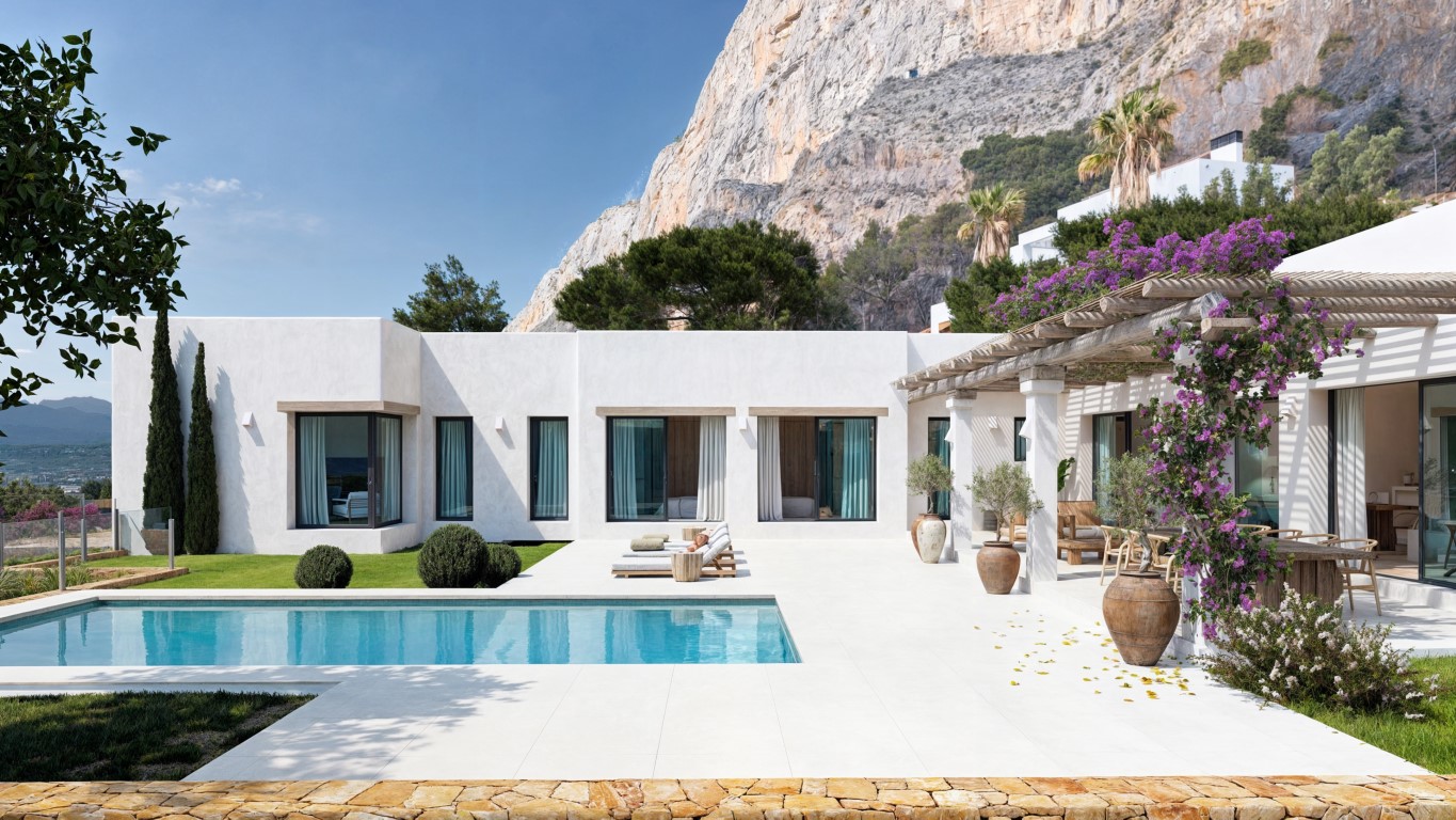 Fachada blanca de estilo mediterráneo con piscina rectangular, terraza de baldosas claras y pérgola de madera con buganvillas bajo el impresionante macizo del Montgó.