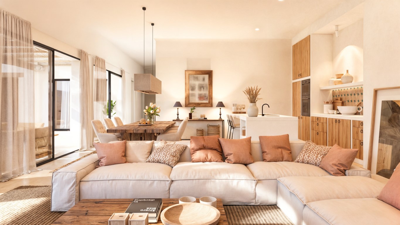 Salón-comedor de concepto abierto con sofá modular, mesa de madera maciza y cocina integrada con isla blanca, conectado a la terraza por grandes ventanales.
