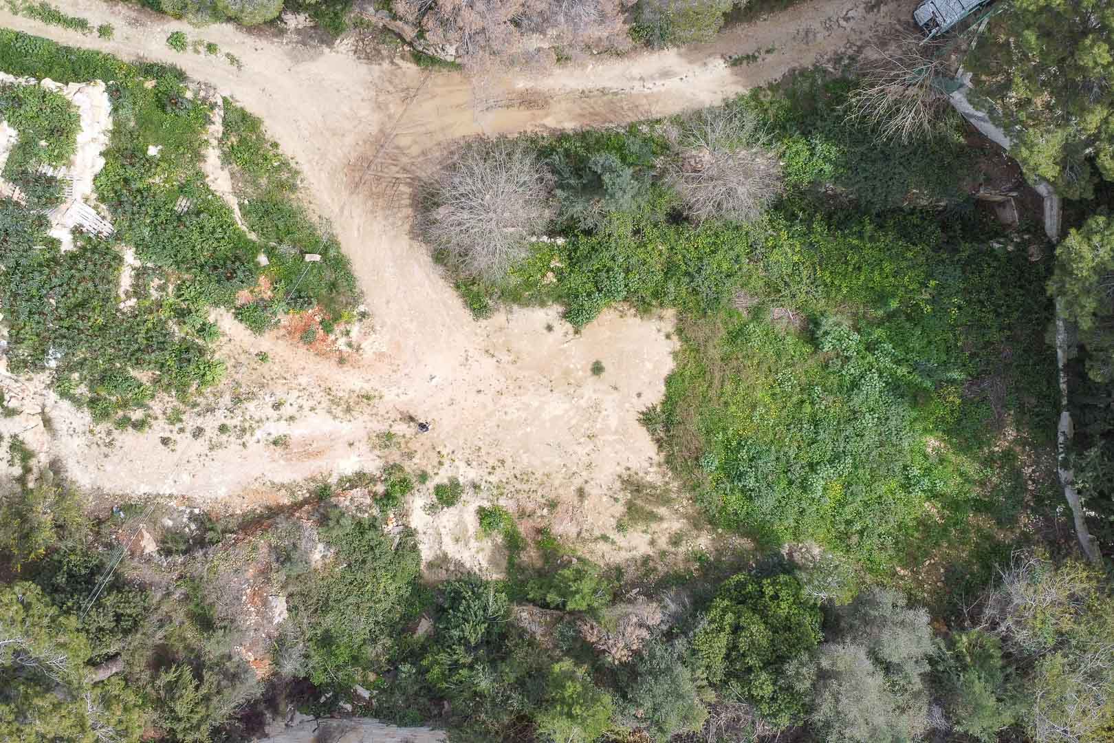 Vista aérea cenital de la parcela en bruto, mostrando la vegetación autóctona y el terreno nivelado listo para el inicio del proyecto de construcción en La Corona.