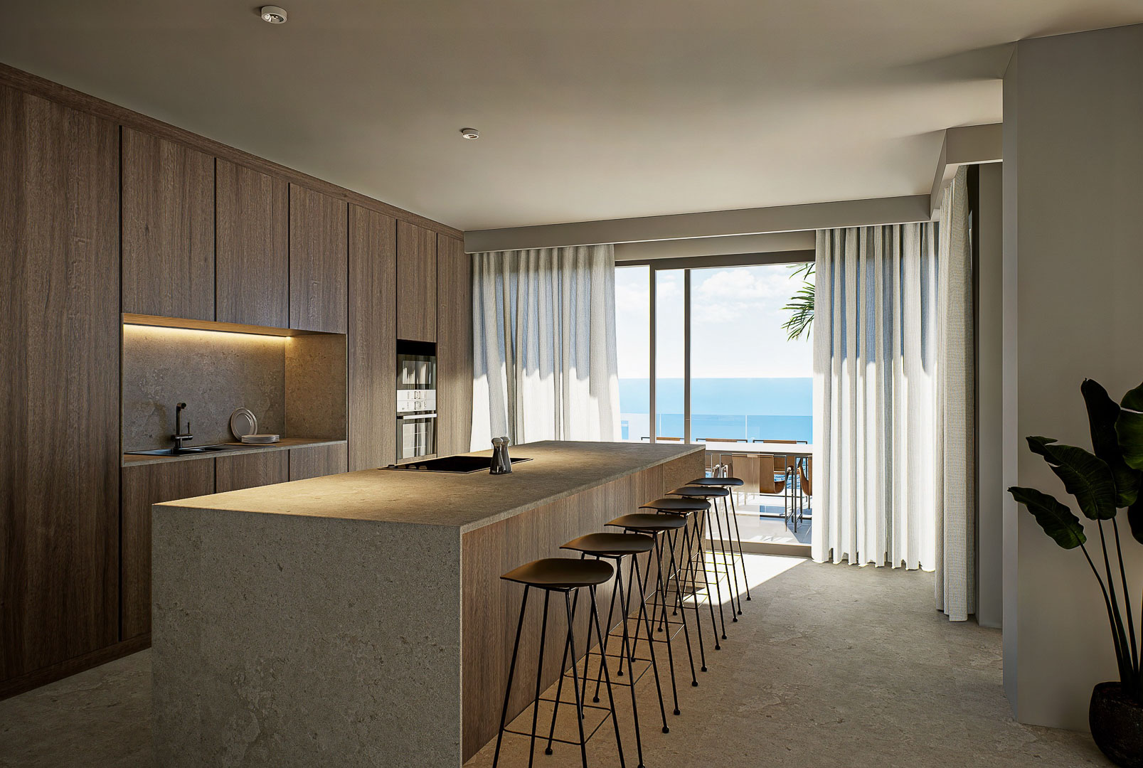 Cocina de diseño con isla central en piedra, armarios de madera natural y acceso directo a la terraza con vistas panorámicas al mar Mediterráneo.