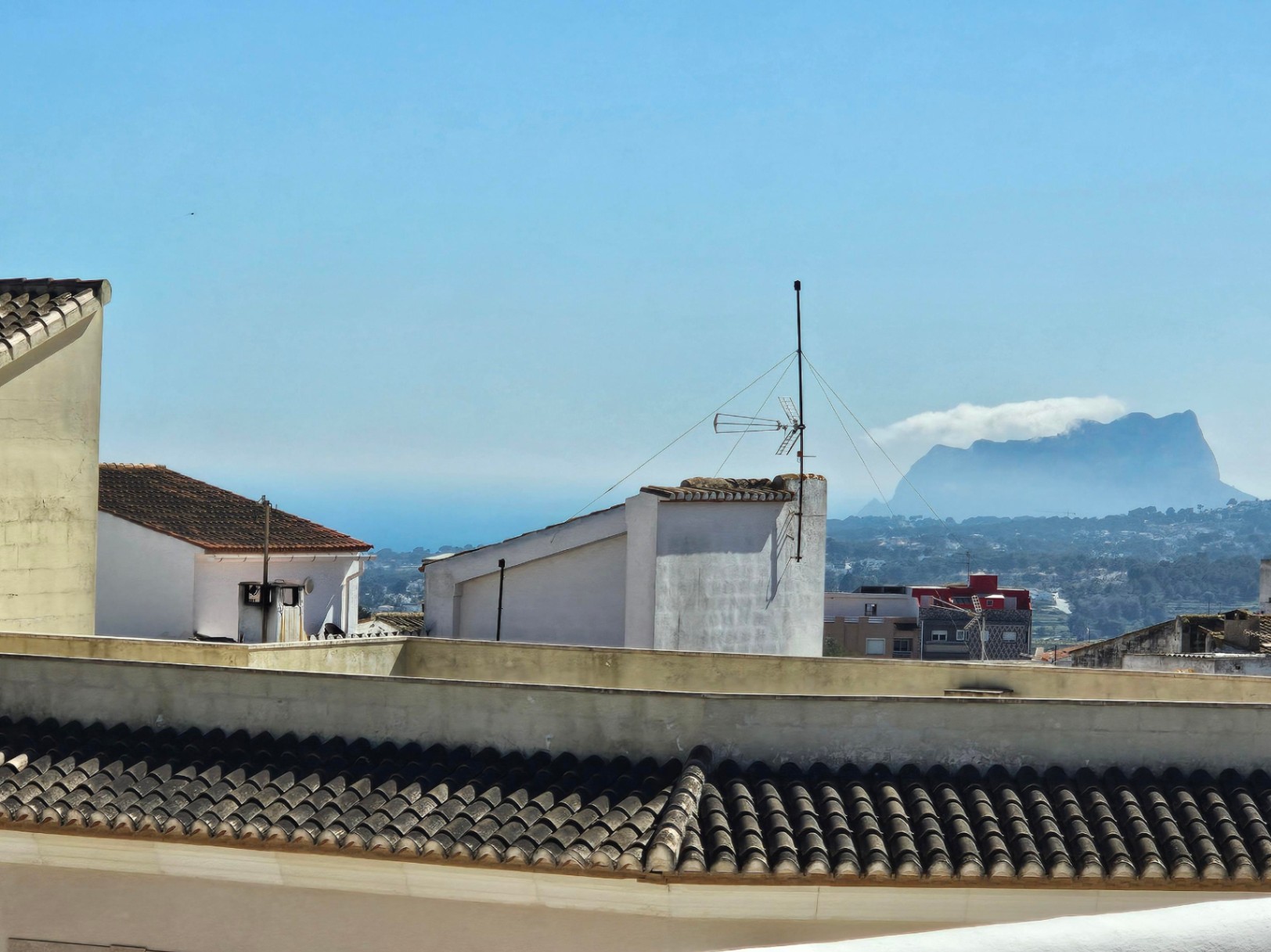 Vistas panorámicas desde la terraza superior hacia los tejados del pueblo, el valle y el mar Mediterráneo, con el Peñón de Ifach destacando en el horizonte.