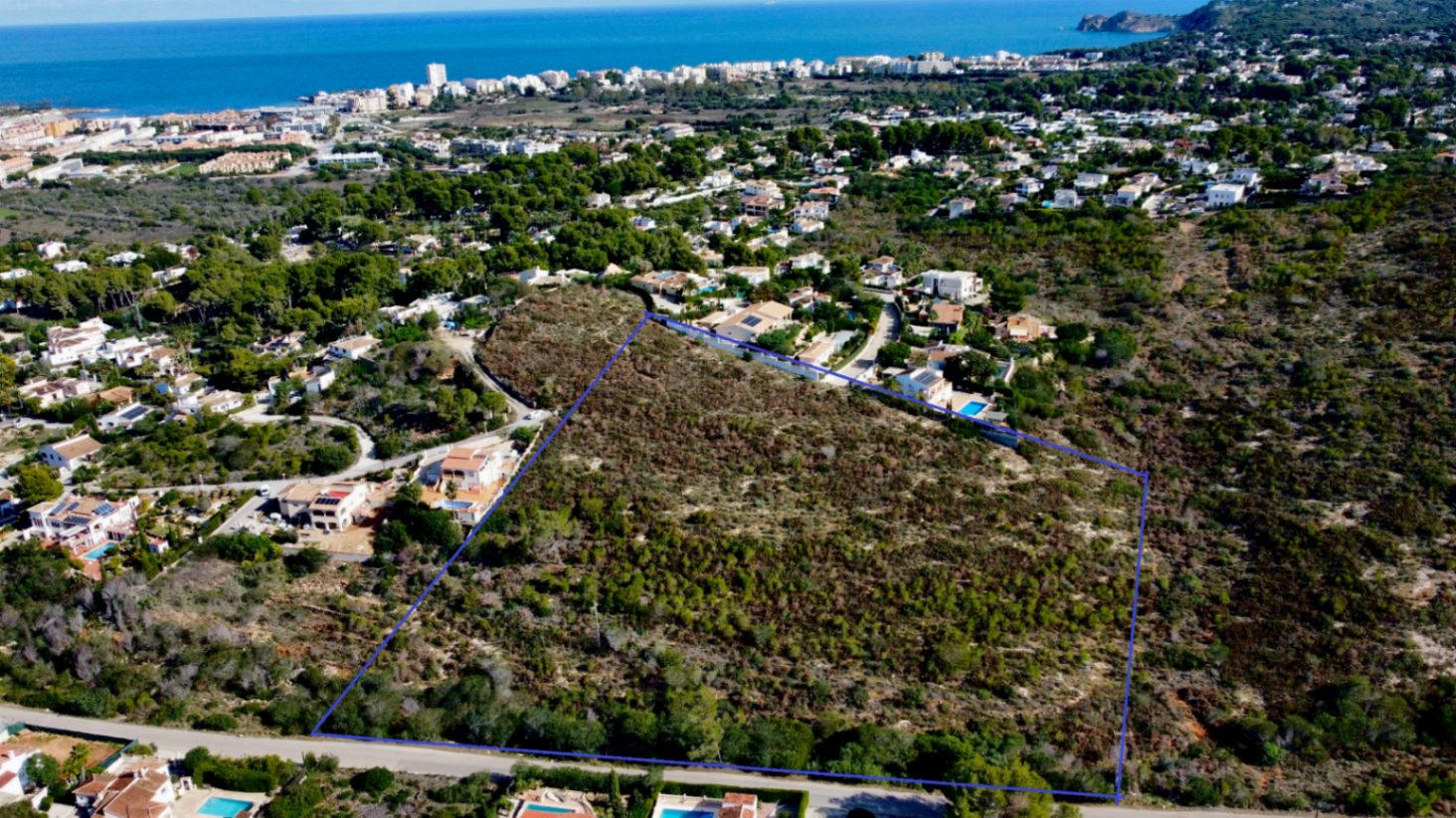 Vista aérea perimetrada de la parcela de 17.272 m² en Jávea, rodeada de vegetación mediterránea y con vistas despejadas hacia la costa y el mar.