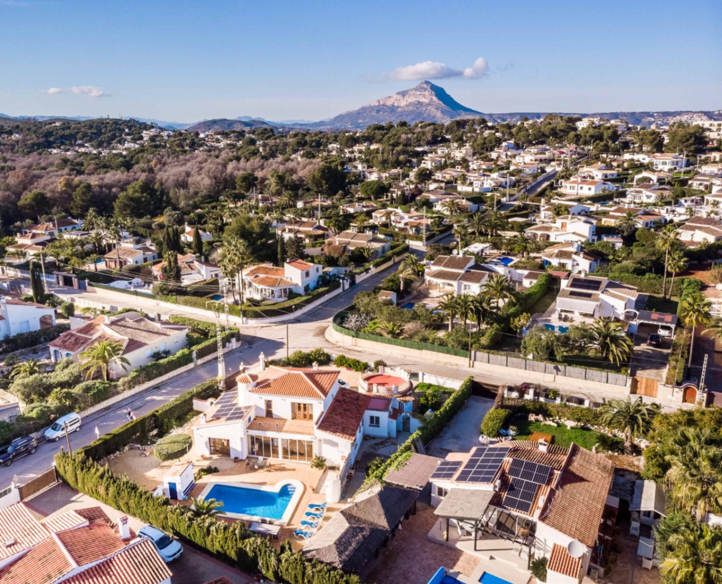 Vista aérea de la villa en Costa Nova Pla mostrando la piscina, paneles solares instalados y el macizo del Montgó al fondo.