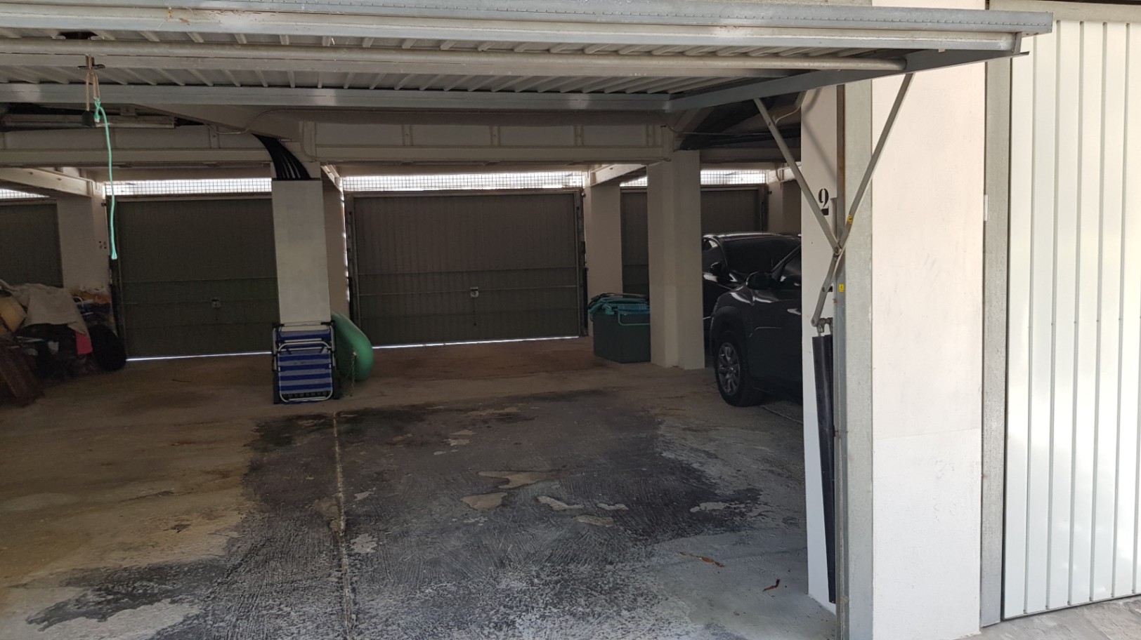 Garaje privado cubierto con suelo de hormigón y puertas metálicas de seguridad, ofreciendo un espacio amplio y protegido para el estacionamiento.
