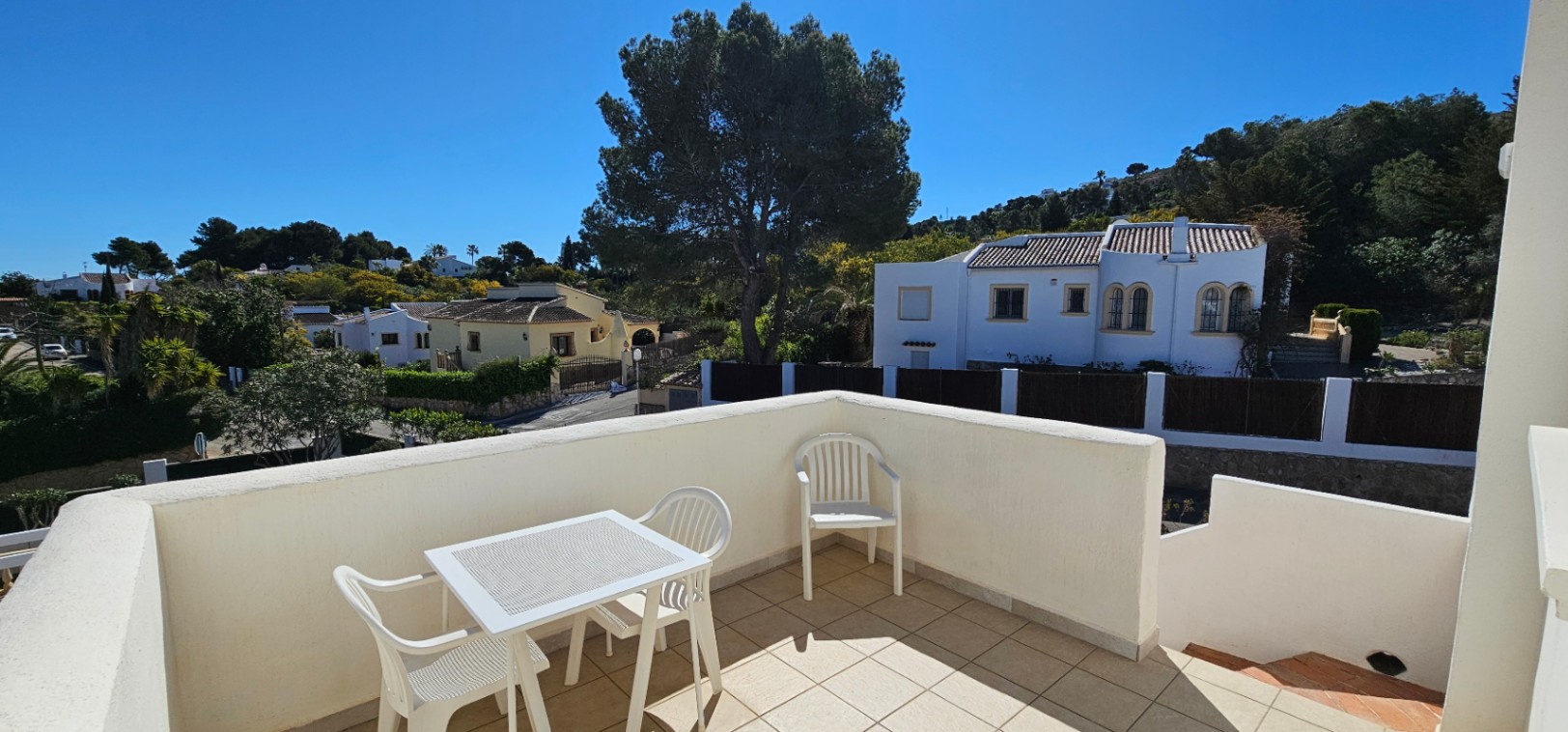 Terraza superior abierta con suelos cerámicos y mobiliario de exterior, ofreciendo vistas despejadas al entorno residencial de Pinosol y las colinas circundantes.