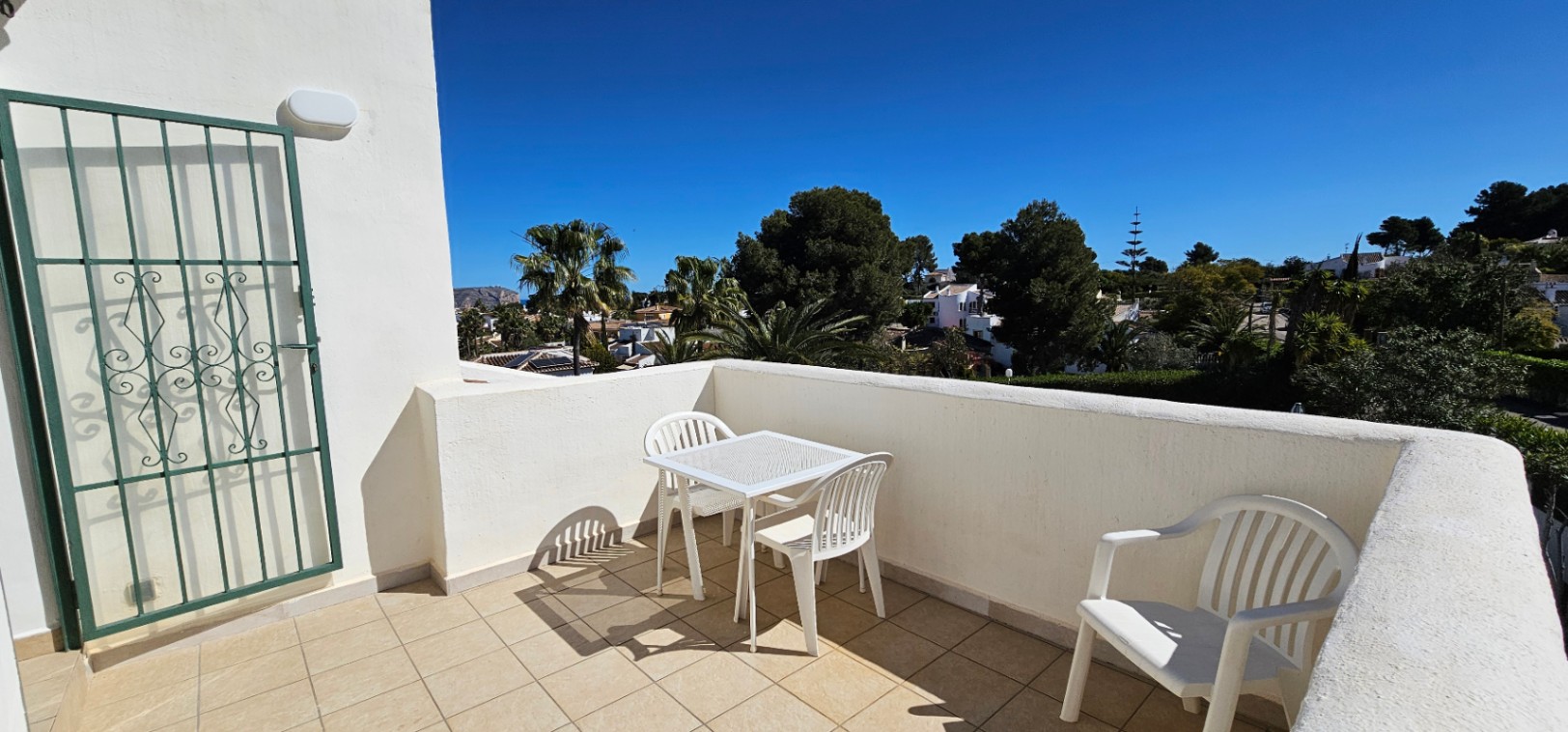 Terraza superior con suelo cerámico, mobiliario de exterior blanco y vistas despejadas a la zona residencial de Pinosol y su entorno arbolado.