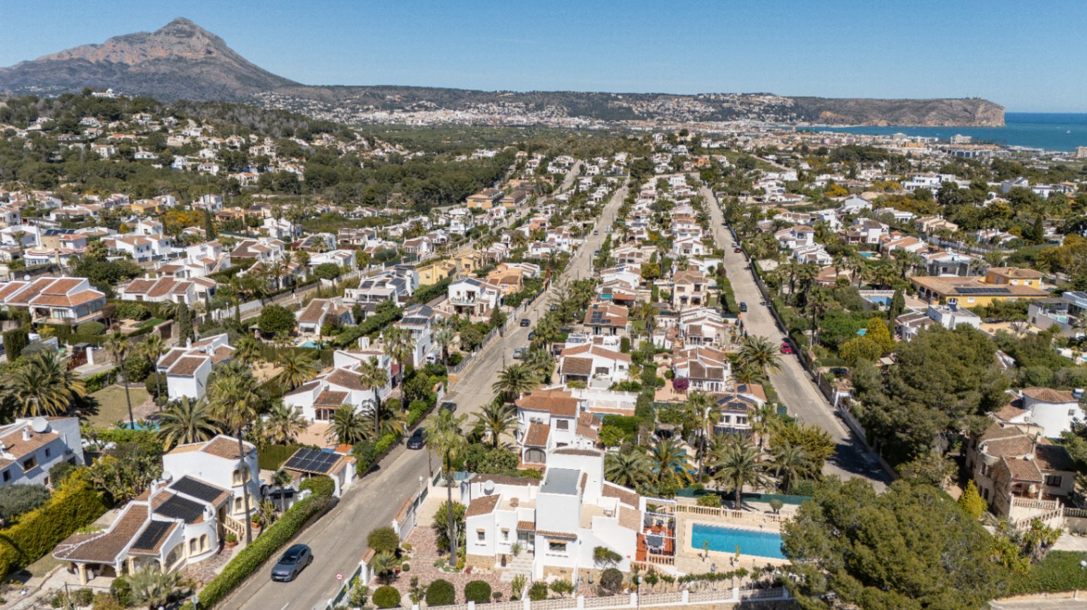 Vista aérea de la urbanización Pinosol en Jávea, destacando la proximidad al mar Mediterráneo y las vistas panorámicas al emblemático macizo del Montgó.