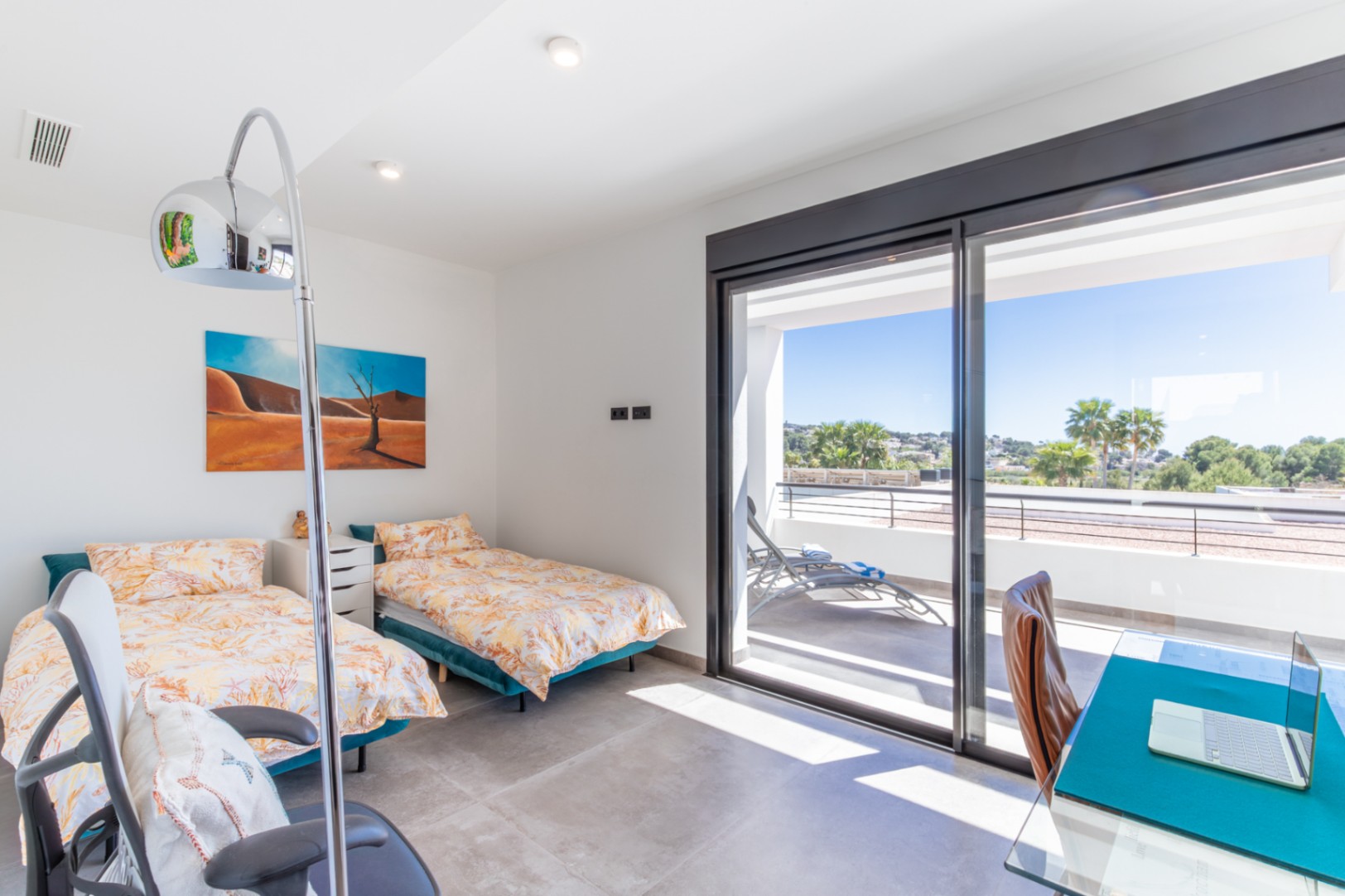 Dormitorio con dos camas individuales, zona de escritorio y acceso directo a una terraza privada con vistas a Moraira a través de ventanales correderos.